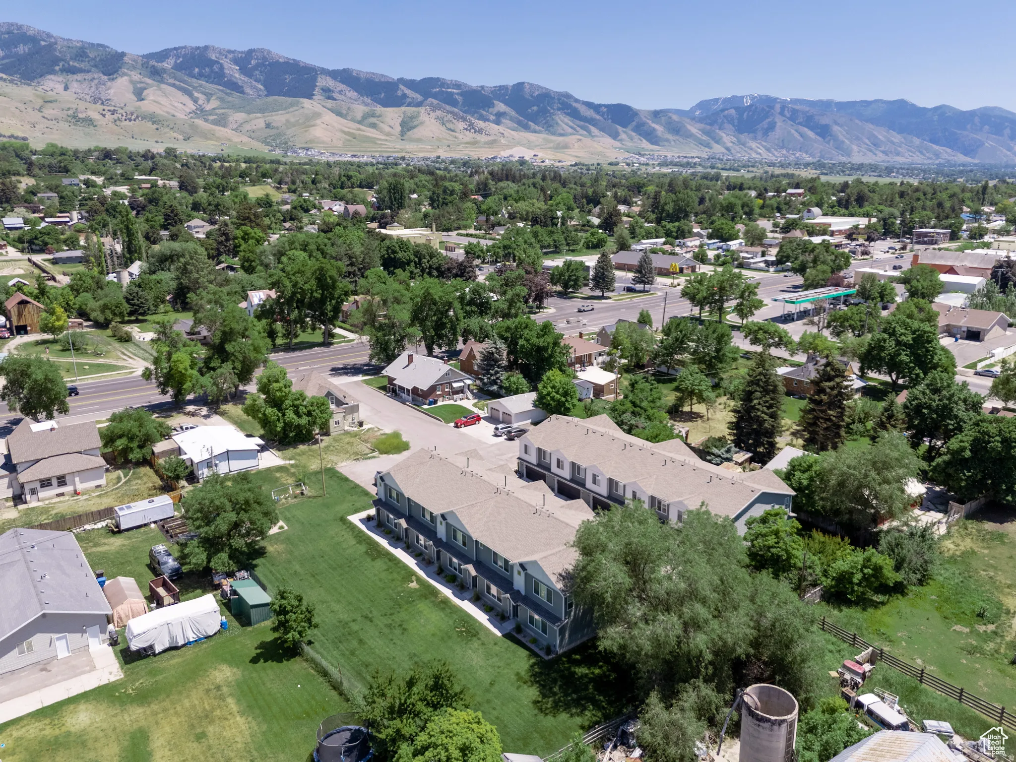 Townhome-style structures featuring multi-story designs, gabled roofs, and an expansive grassy area