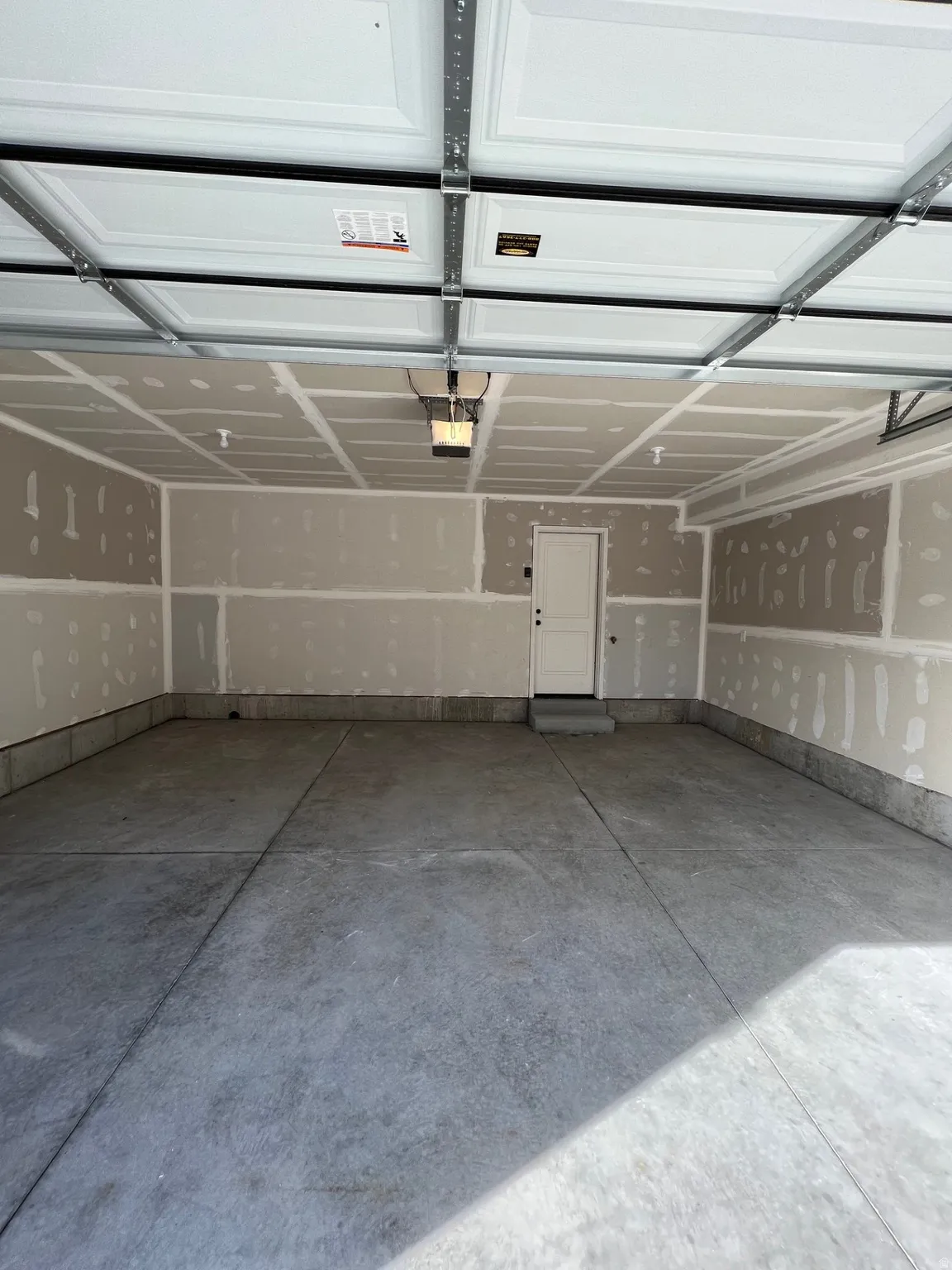 Spacious two-car garage featuring a concrete floor, an overhead garage door opener, and a panel-style garage door