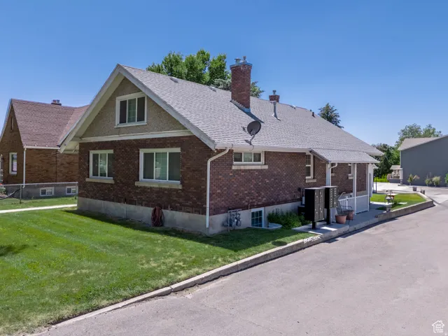 Brick exterior featuring a gabled roofline and a well-maintained lawn