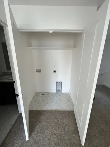 Dedicated utility closet featuring a built-in shelf, clothing rod, and tiled flooring