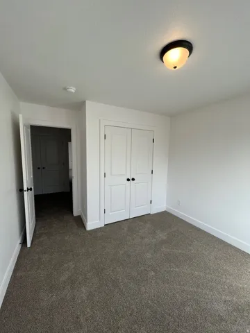 Neutral carpeted room featuring white walls and trim