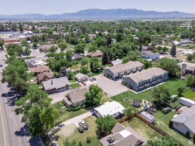 Expansive aerial capturing residential properties, green spaces, and a mountainous backdrop