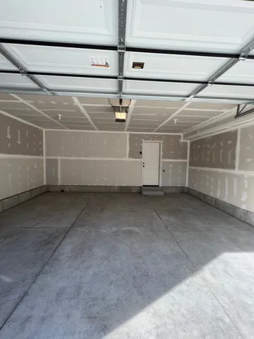 Spacious two-car garage featuring a concrete floor, an overhead garage door opener, and a panel-style garage door