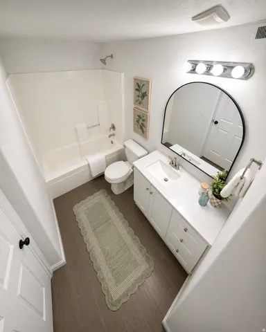 Bathroom featuring a white vanity with a quartz-finish countertop, single basin sink, and chrome fixtures
