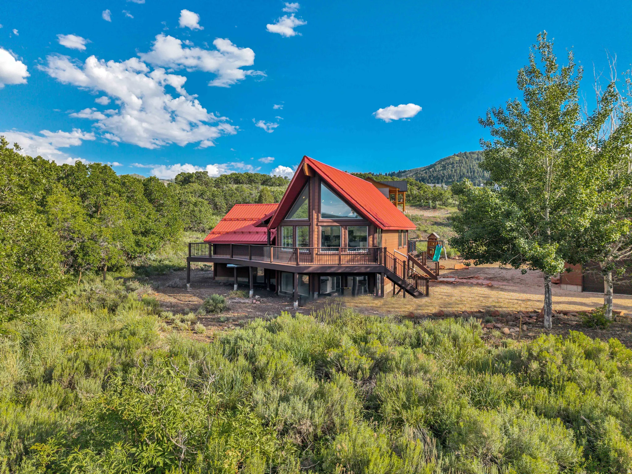 Cabin-style residence featuring a prominent red metal roof and extensive decking