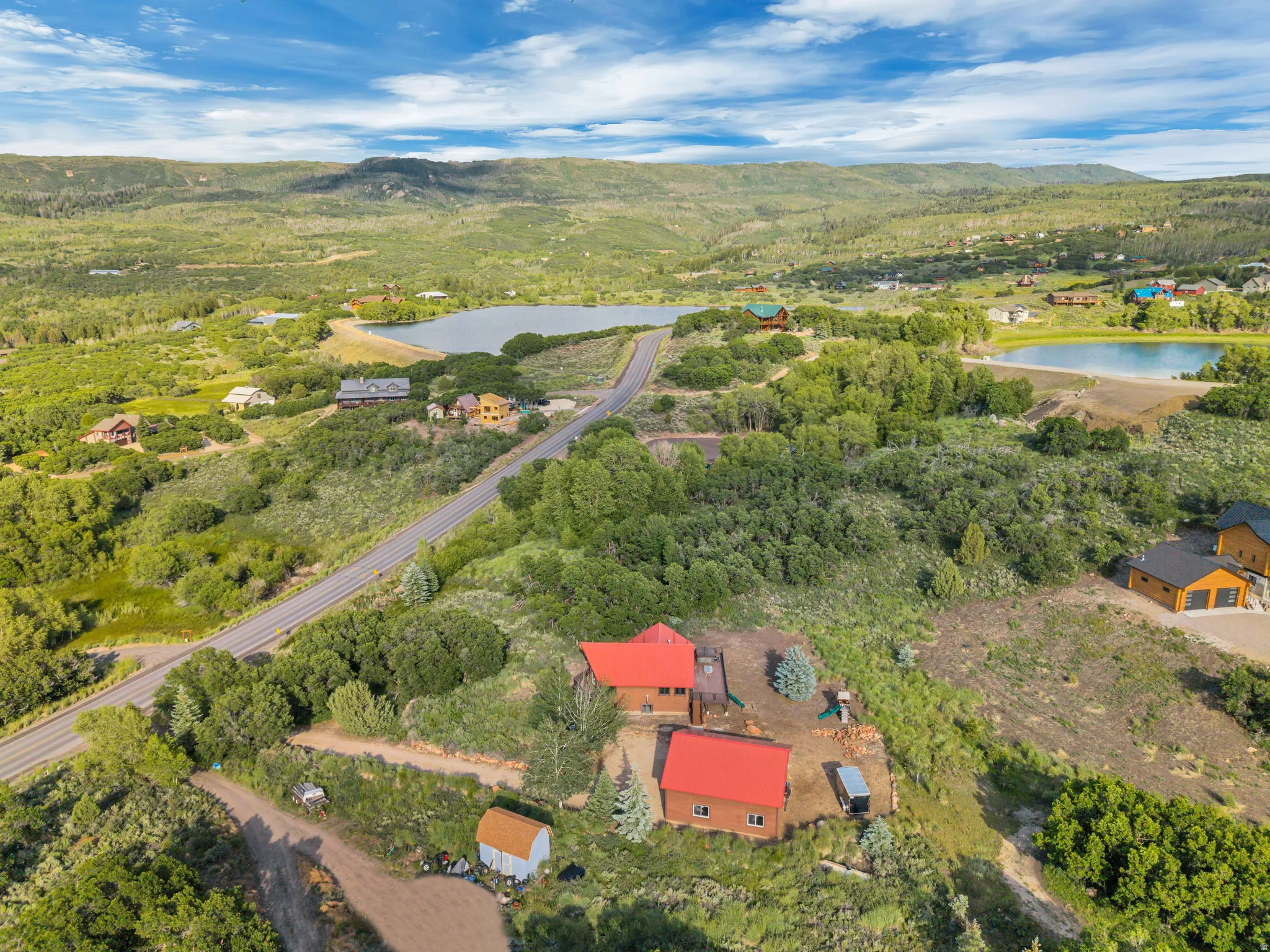 Aerial perspective showcasing a residential property with a red metal roof, surrounded by natural landscaping