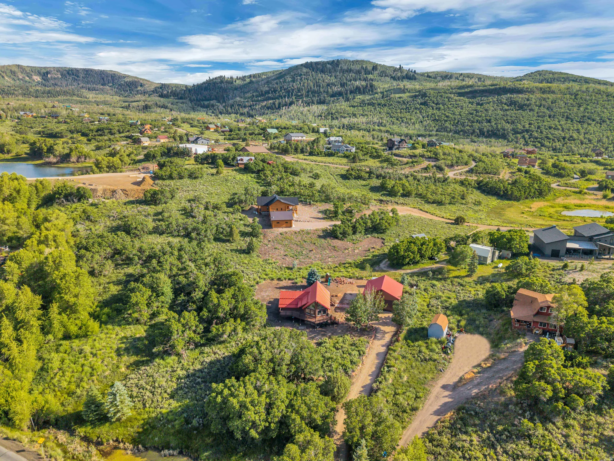 Mountainous landscape featuring multiple properties, extensive green foliage, and distant water bodies