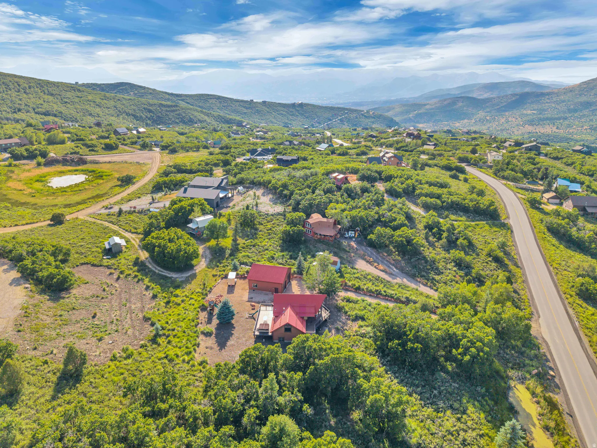 Aerial perspective showcasing a residential property with a red roof, surrounded by extensive green landscaping and mature trees