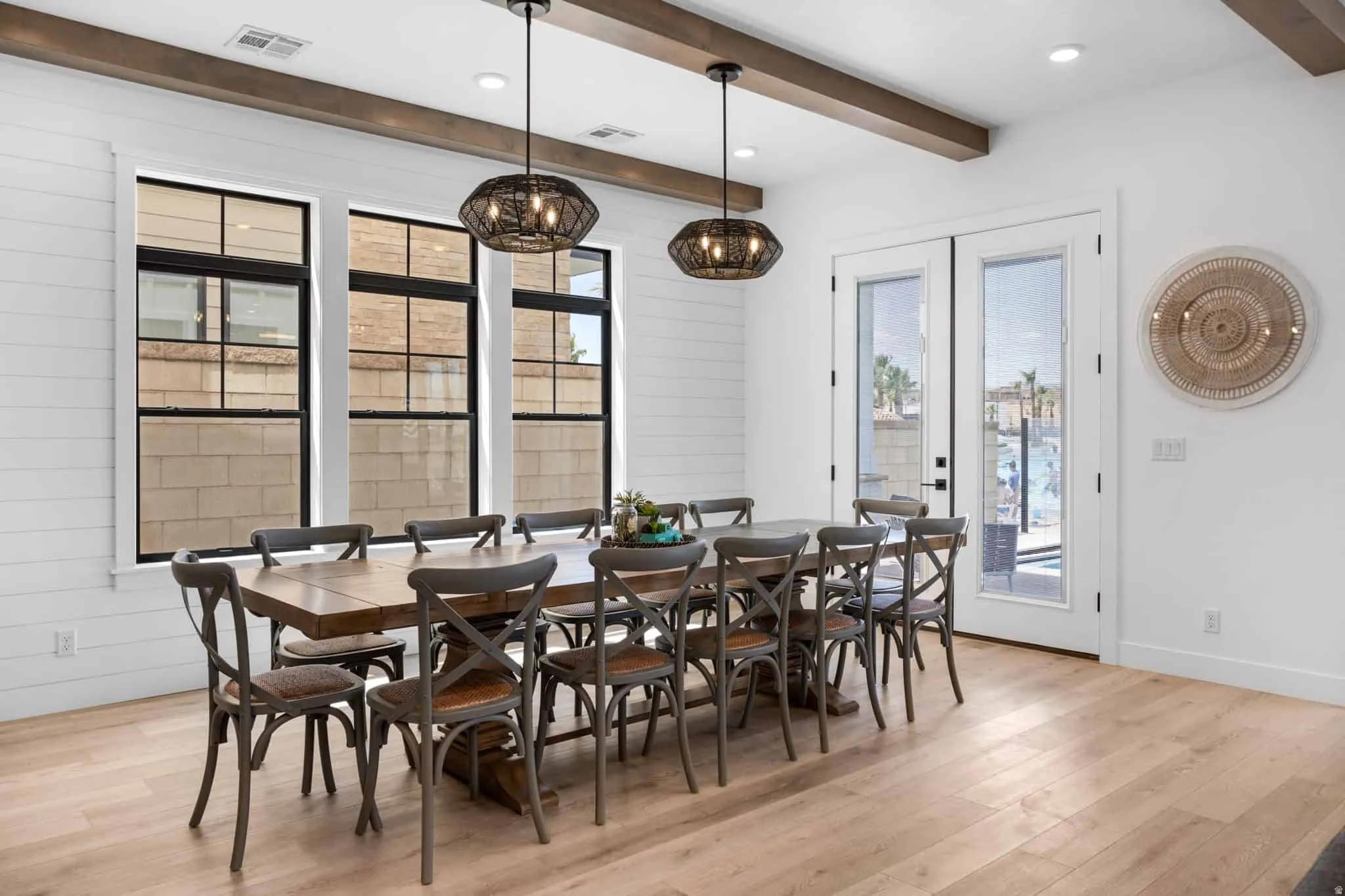 Spacious dining area featuring wood-finish flooring, white shiplap accent wall, and exposed wood beams