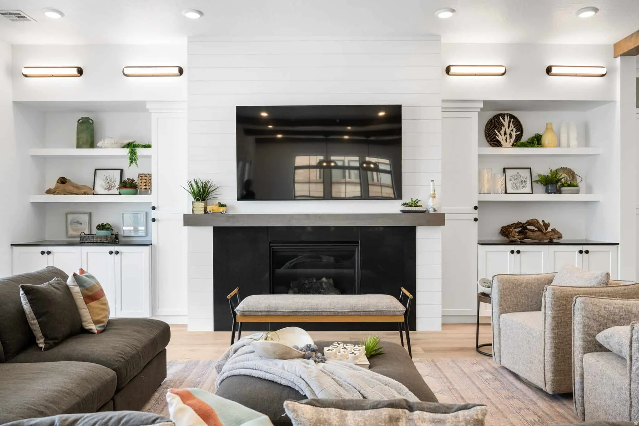 Living area featuring a fireplace with a dark surround and concrete-finish mantel, flanked by built-in shelving and cabinetry with dark countertops