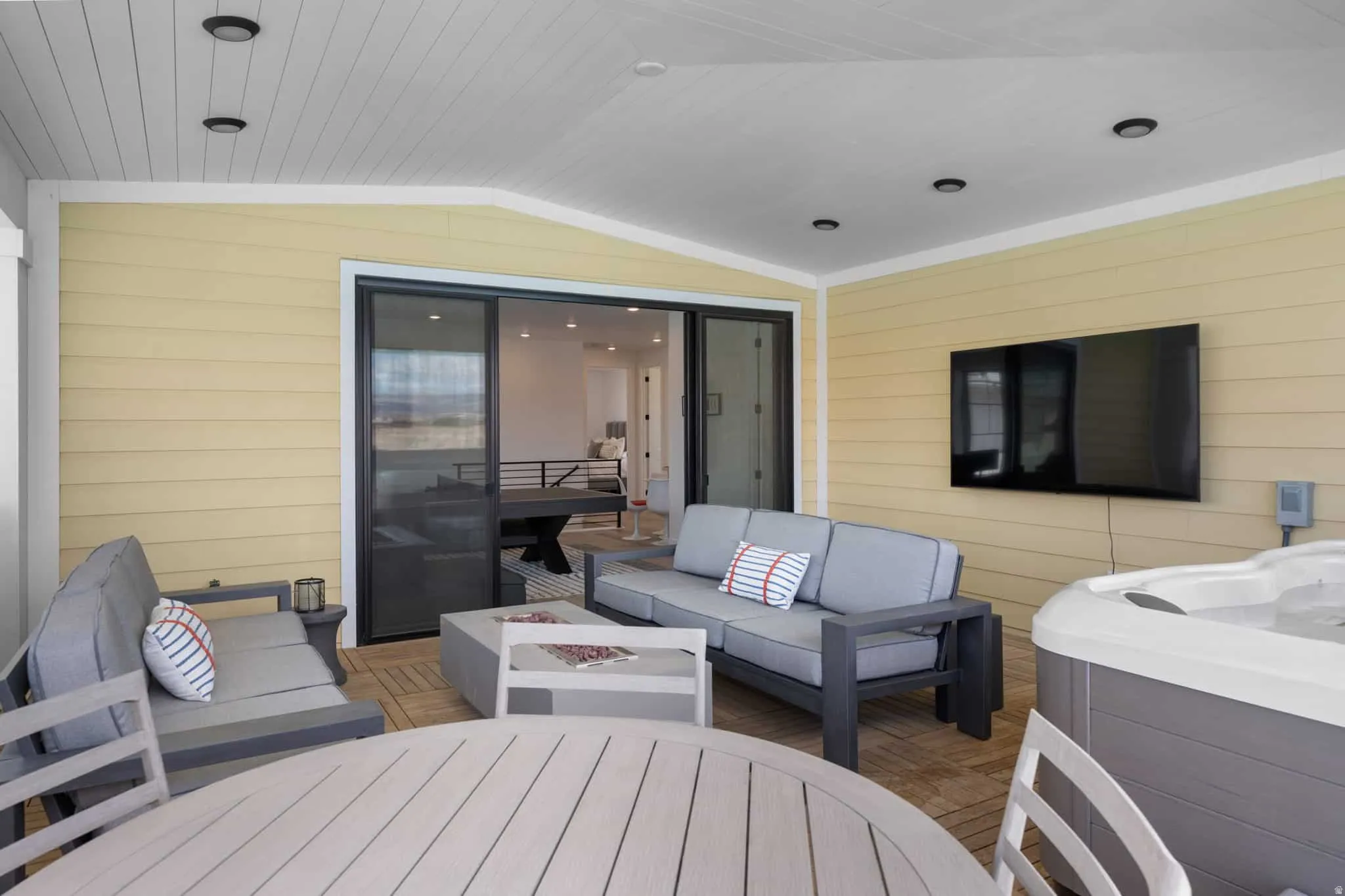 Covered patio featuring a hot tub, mounted television, and wood-finish flooring