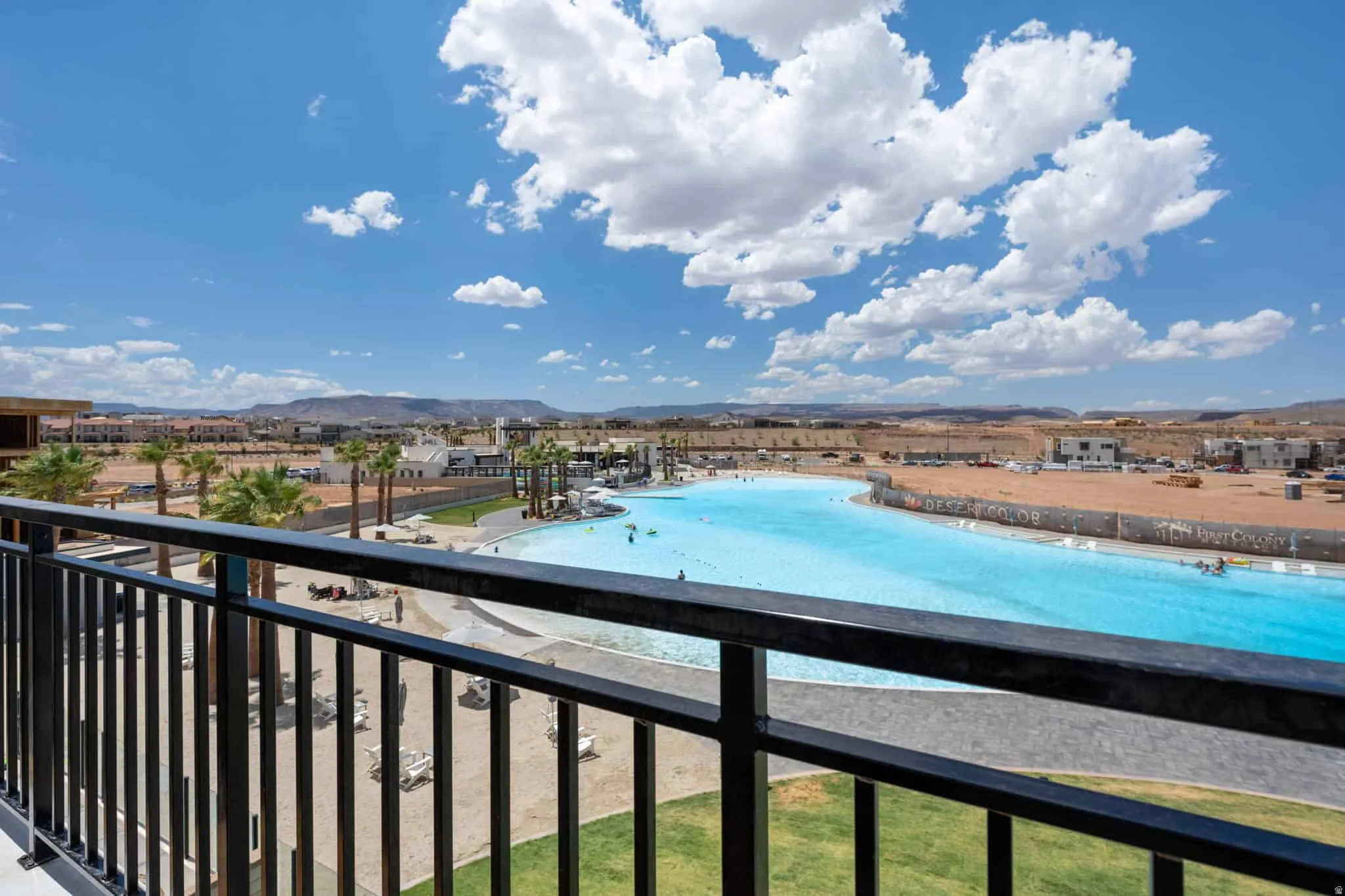 Balcony with black metal railing overlooking a large lagoon-style pool
