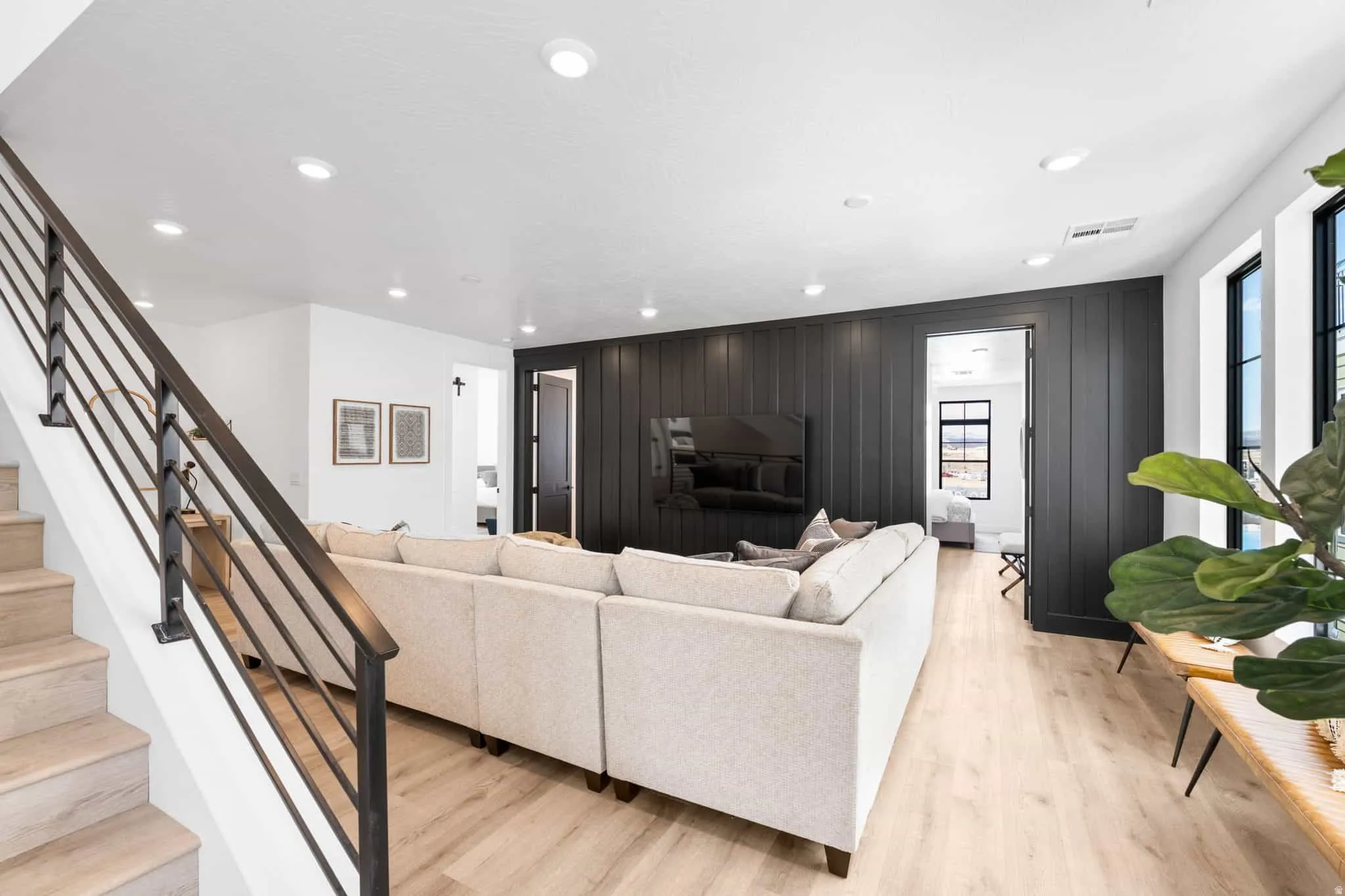 Open-concept living space with light wood-finish flooring, recessed lighting, and a contemporary dark wood-paneled accent wall