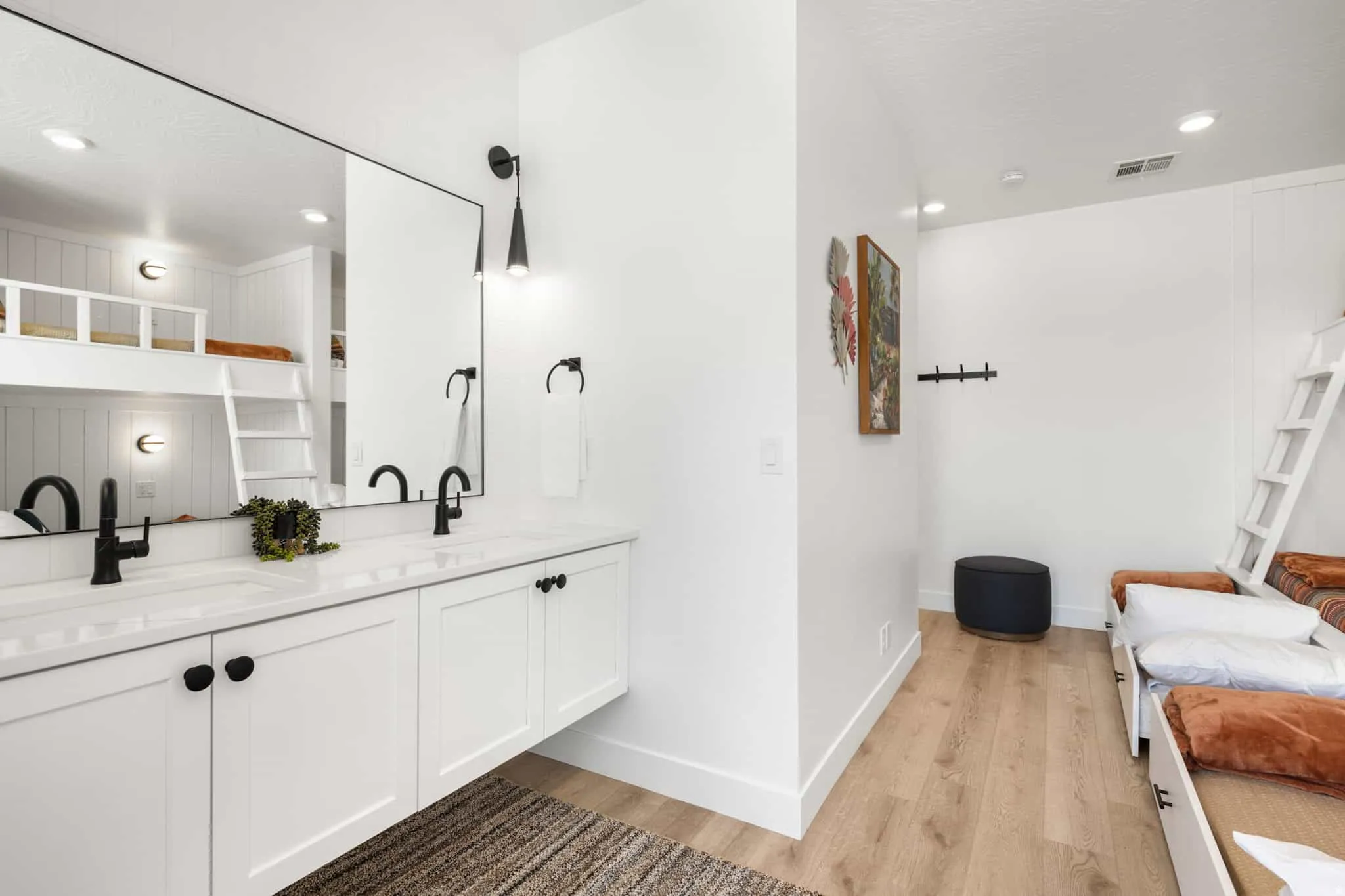 Double vanity with white cabinetry, matte black hardware, and an expansive mirror