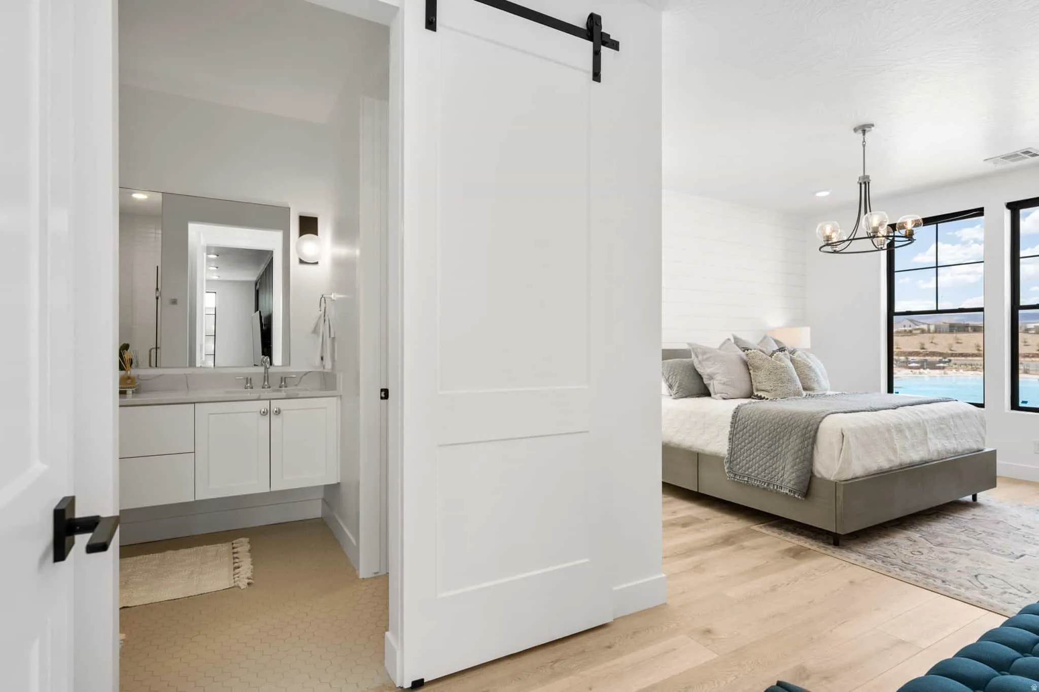 White barn door entrance to a bedroom featuring light wood-finish flooring and large windows