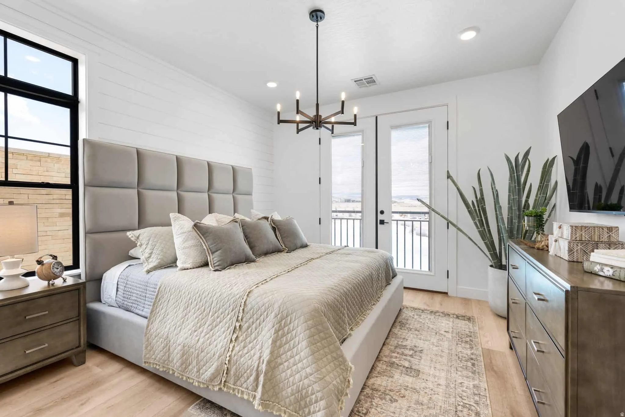 Spacious room featuring light wood-finish flooring, a contemporary chandelier, recessed lighting, and a white shiplap accent wall