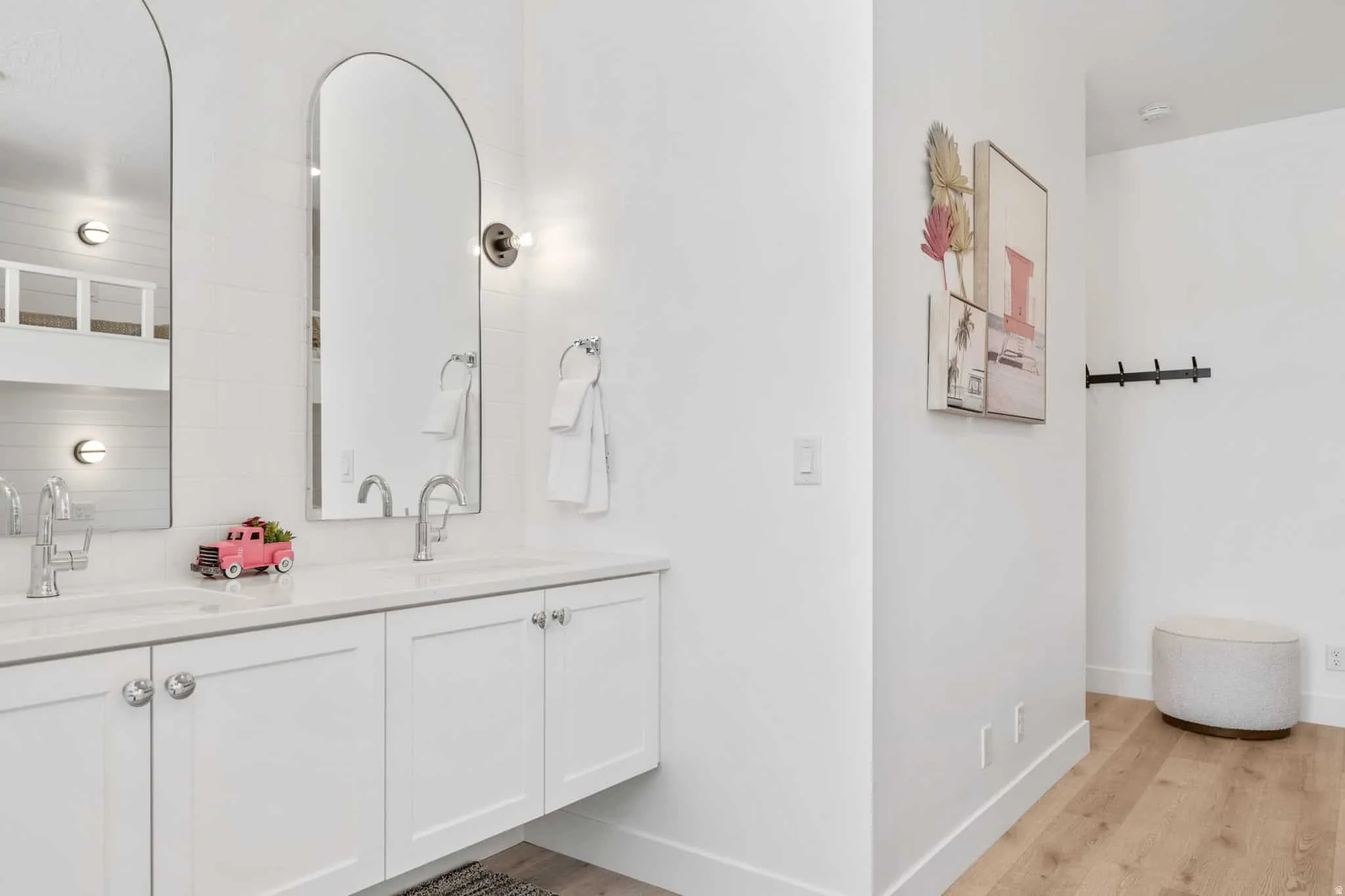 Dual vanity with white cabinetry, polished chrome hardware, and arched mirrors