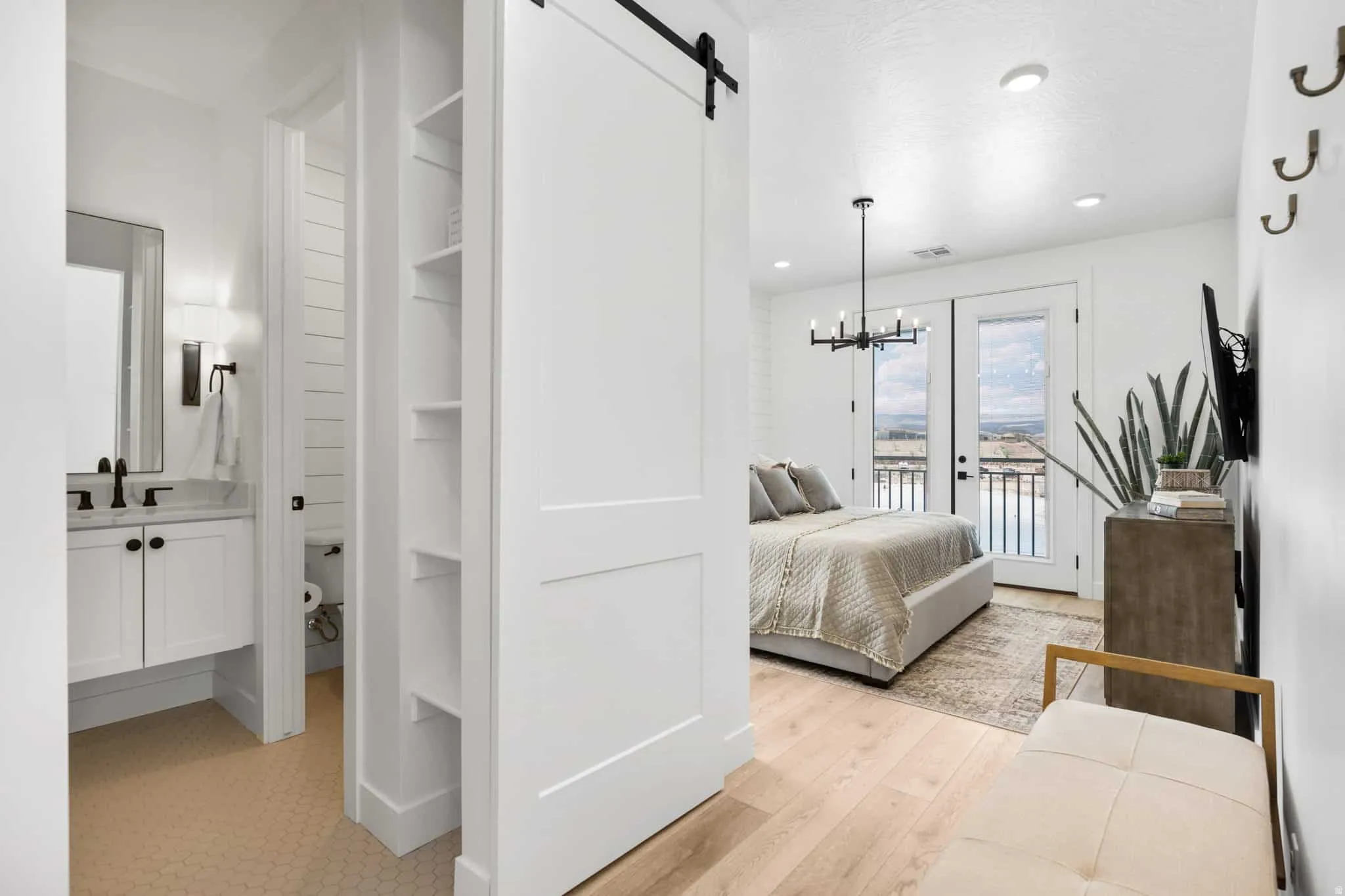 Bright bedroom featuring light wood-finish flooring and a contemporary chandelier