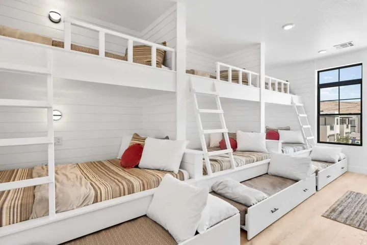 Built-in bunk beds featuring integrated lighting, shiplap wall finishes, natural wood-finish flooring, and a large black-framed window