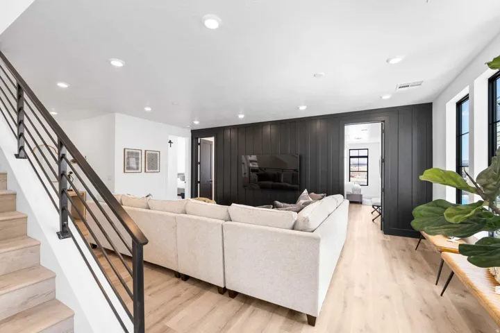 Open-concept living space with light wood-finish flooring, recessed lighting, and a contemporary dark wood-paneled accent wall