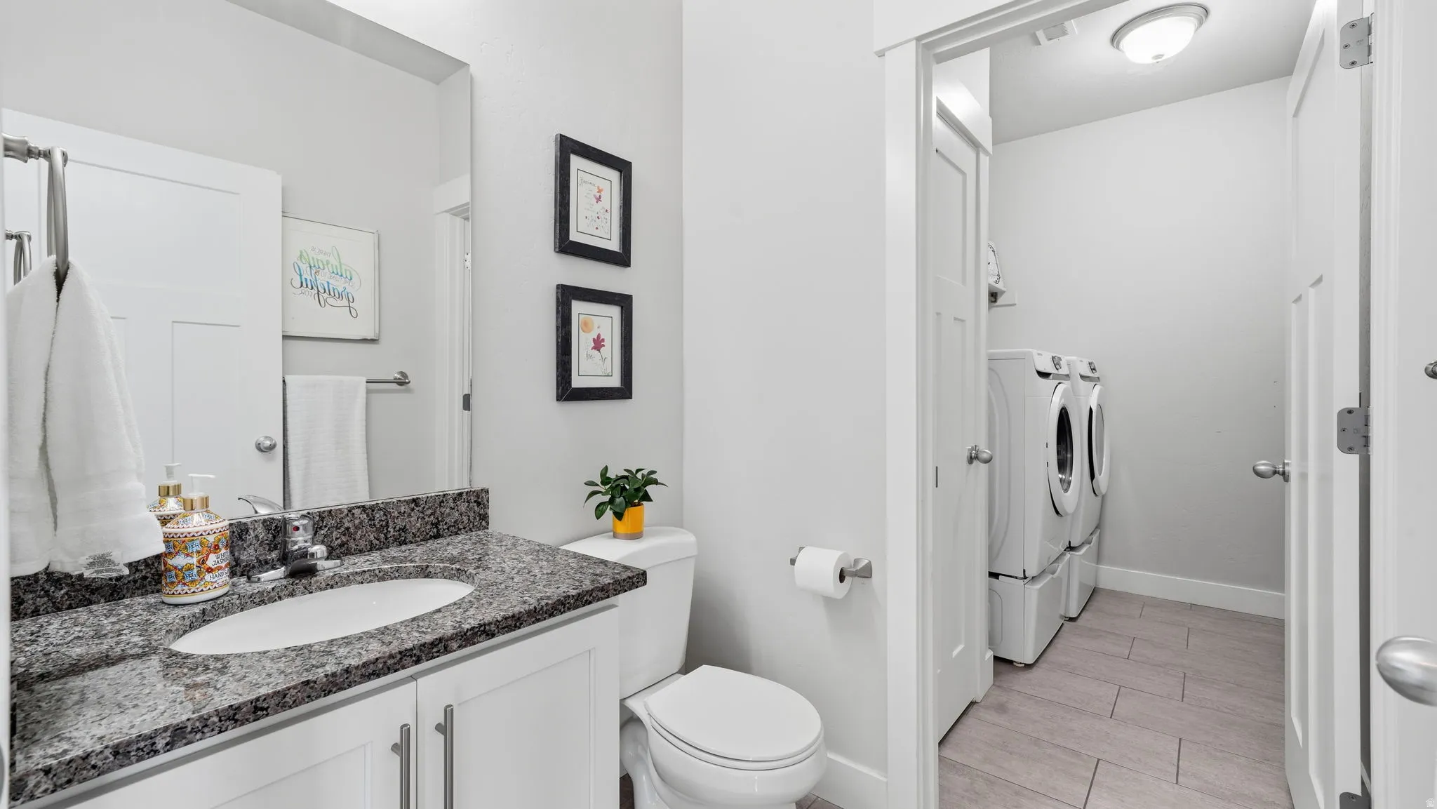 Bathroom featuring a white vanity with a dark speckled countertop, an oval undermount sink, and a chrome faucet