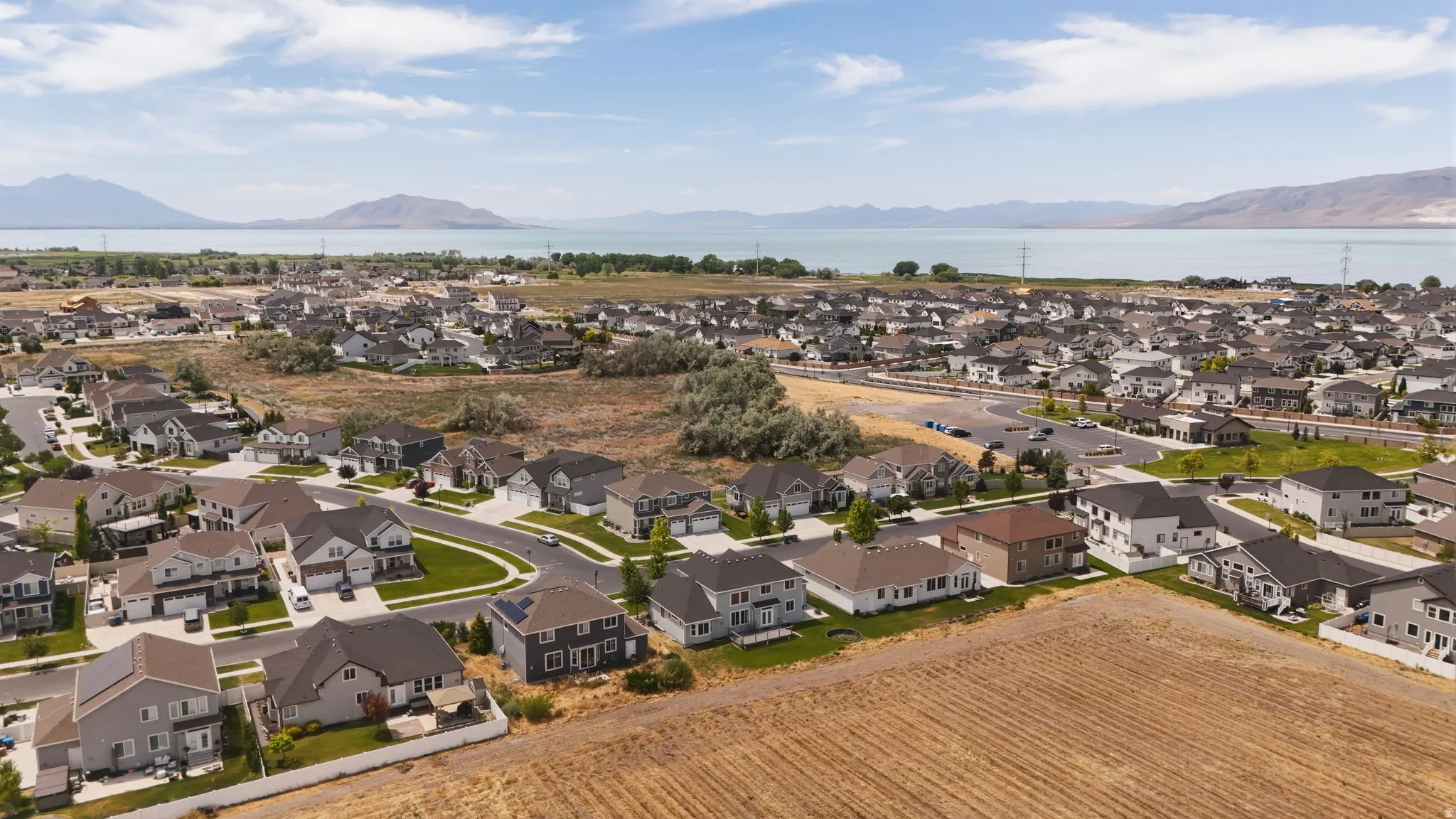 Expansive aerial perspective showcasing a residential development with a lake and mountains in the background
