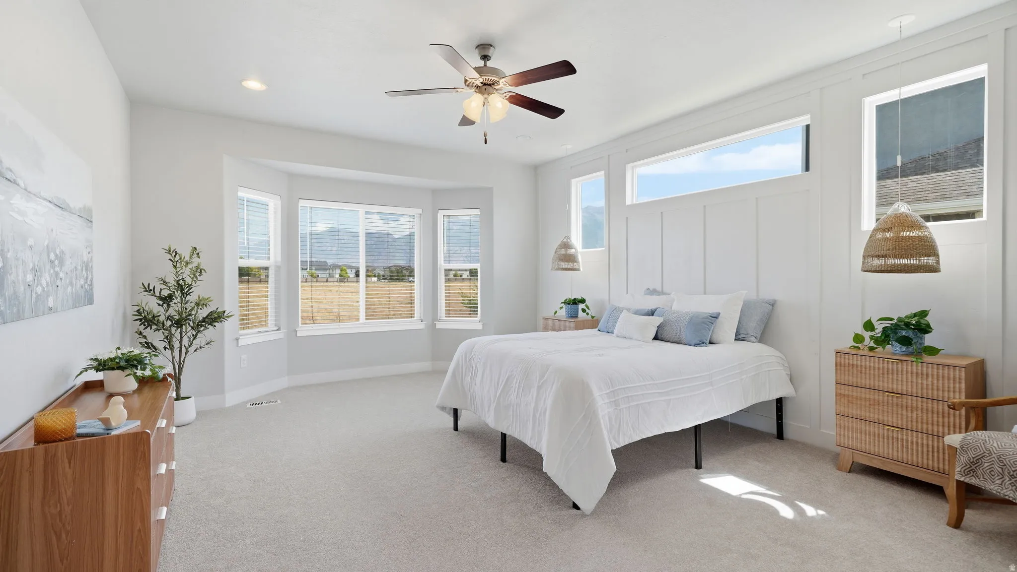 Spacious bedroom featuring light-colored carpeting and a ceiling fan