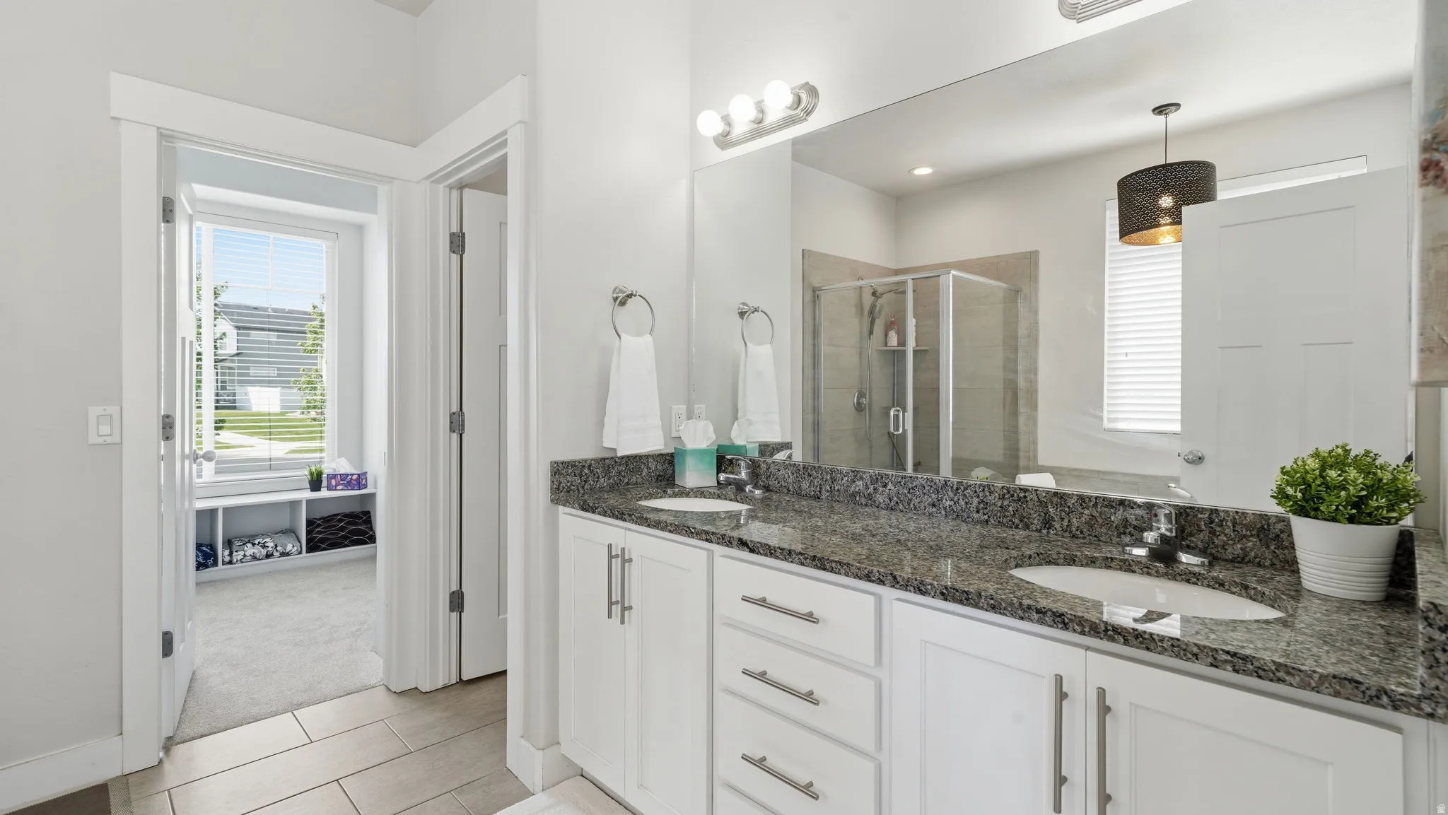Double vanity with granite countertop, white cabinetry, and brushed nickel hardware