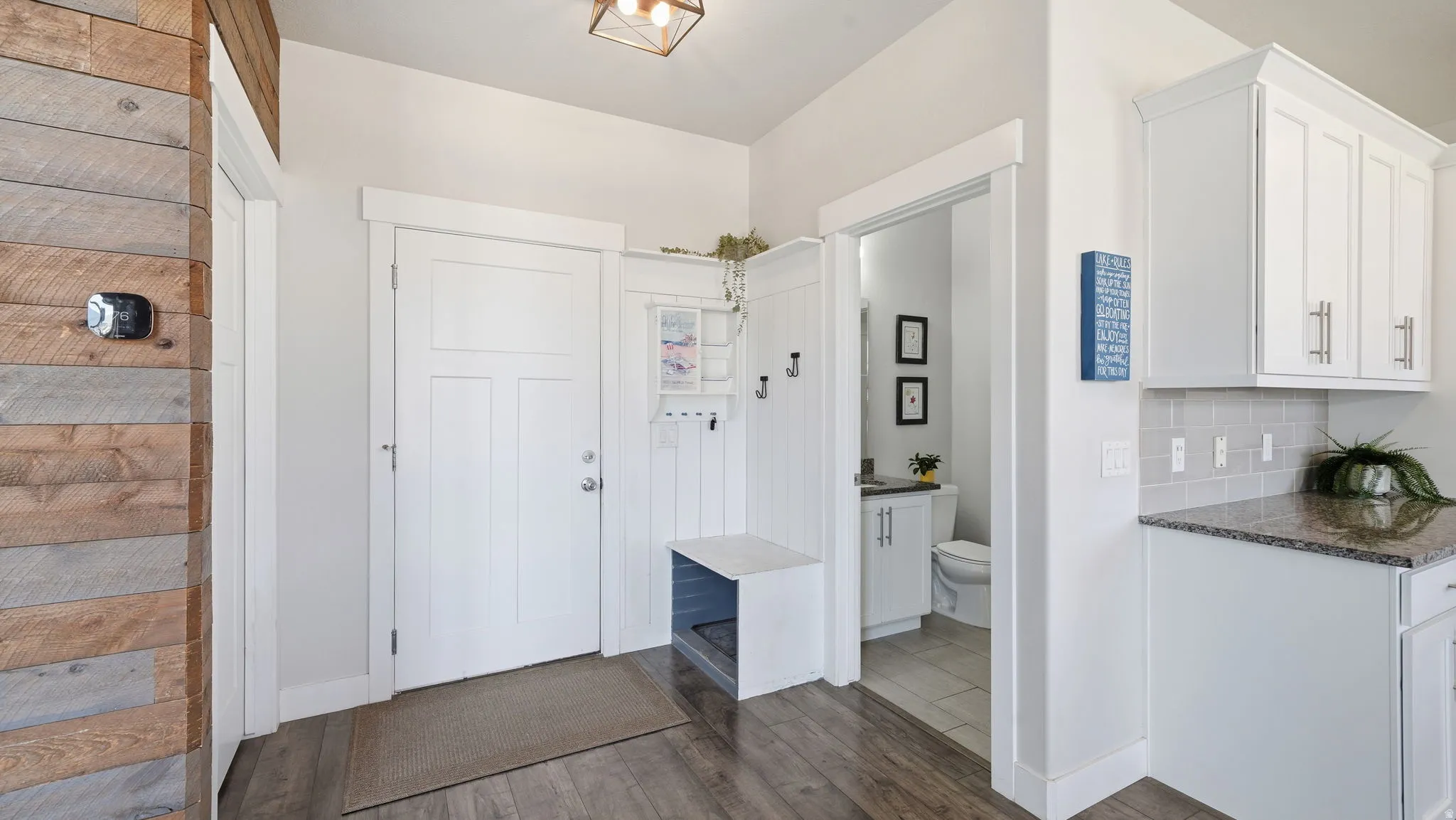 Entryway featuring wood-finish flooring, a white panel door, and a built-in mudroom bench with coat hooks