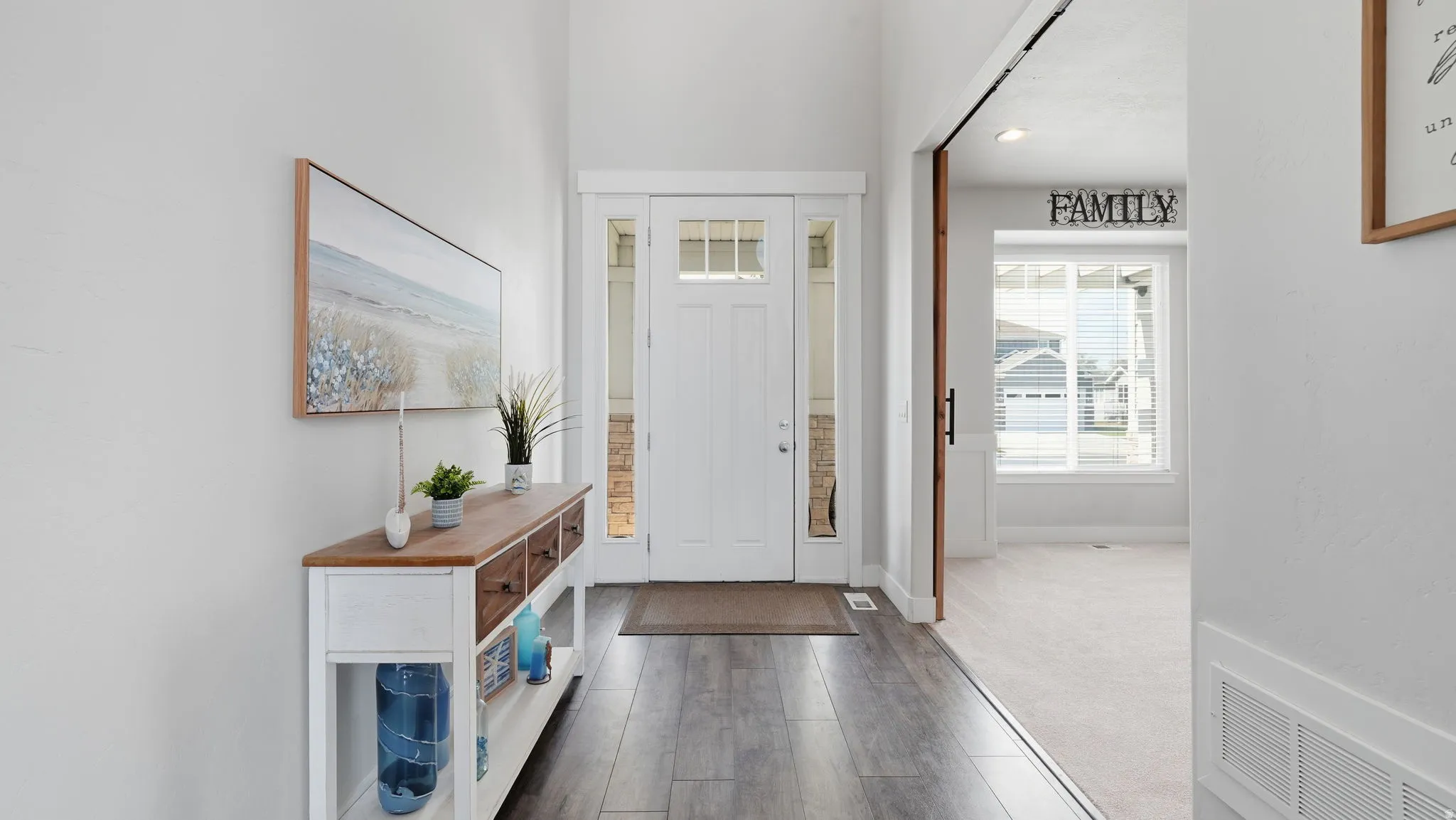 Inviting entryway featuring wood-finish flooring, a white front door with transom and sidelight windows, and light neutral wall paint