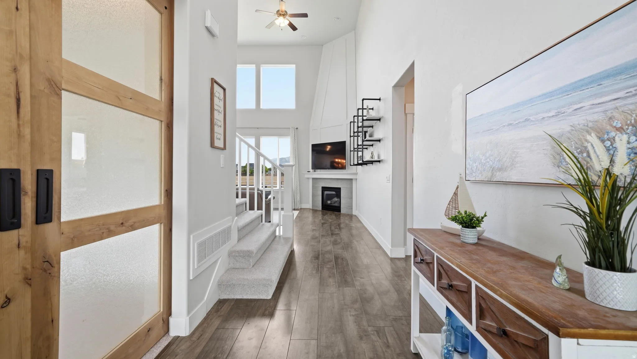 Spacious entryway with wood-finish flooring, a contemporary barn door featuring frosted glass panels, and a staircase with carpeted treads