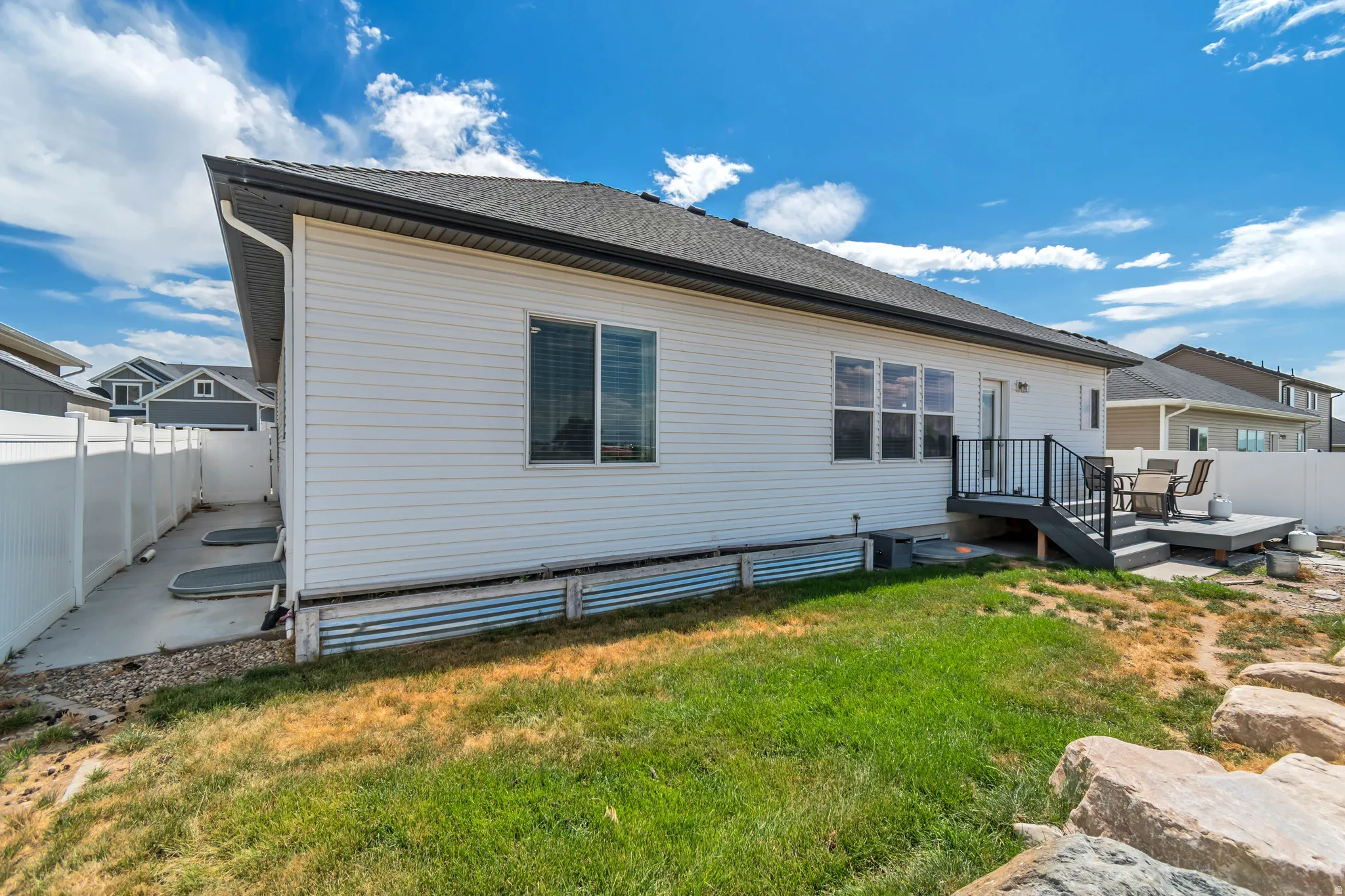 Rear exterior featuring white horizontal siding, a dark shingle roof, and a gray composite deck with black railings