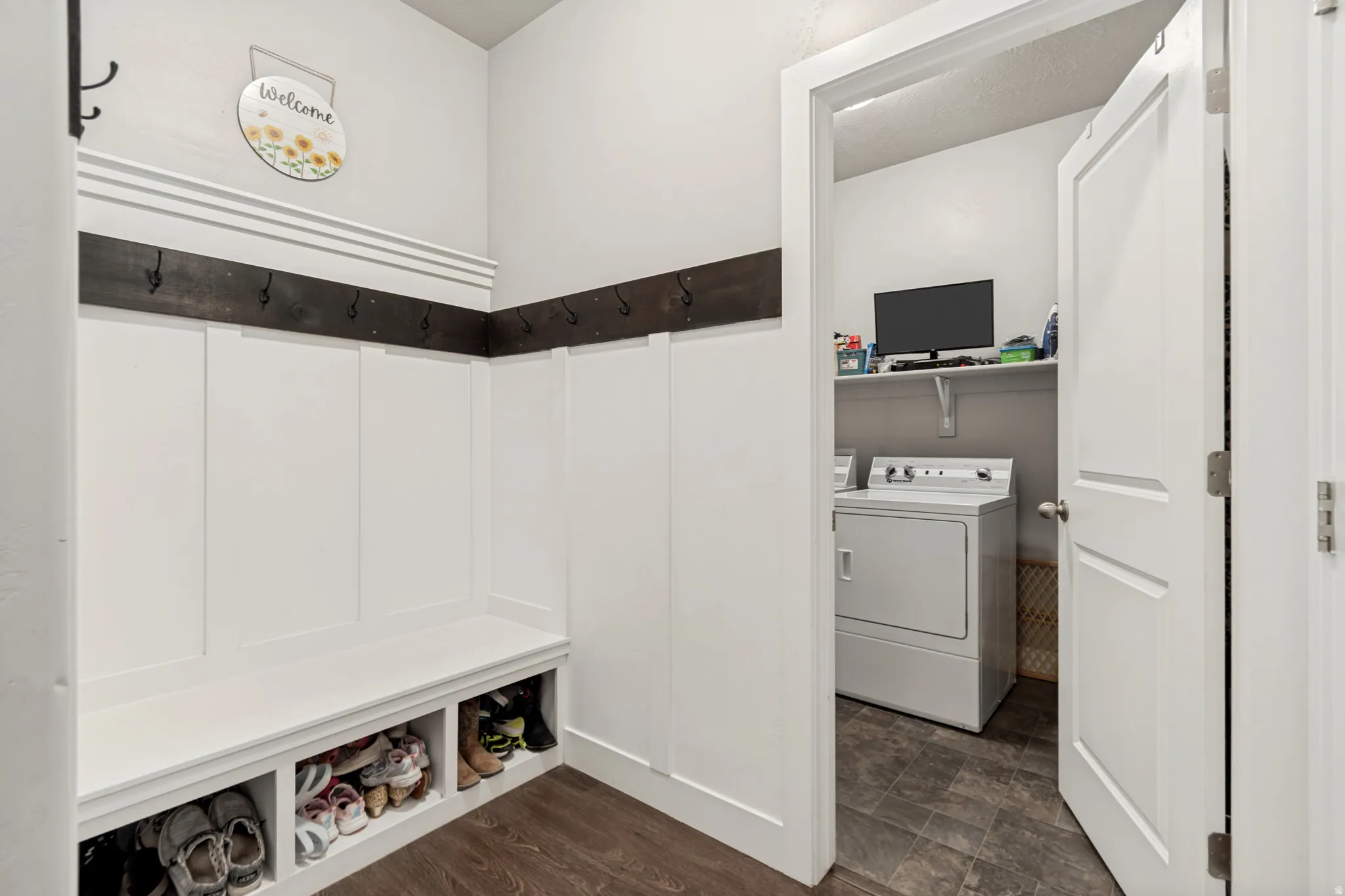 Entryway featuring white wainscoting, a built-in bench with cubby storage, and a dark wood-finish coat rack with hooks