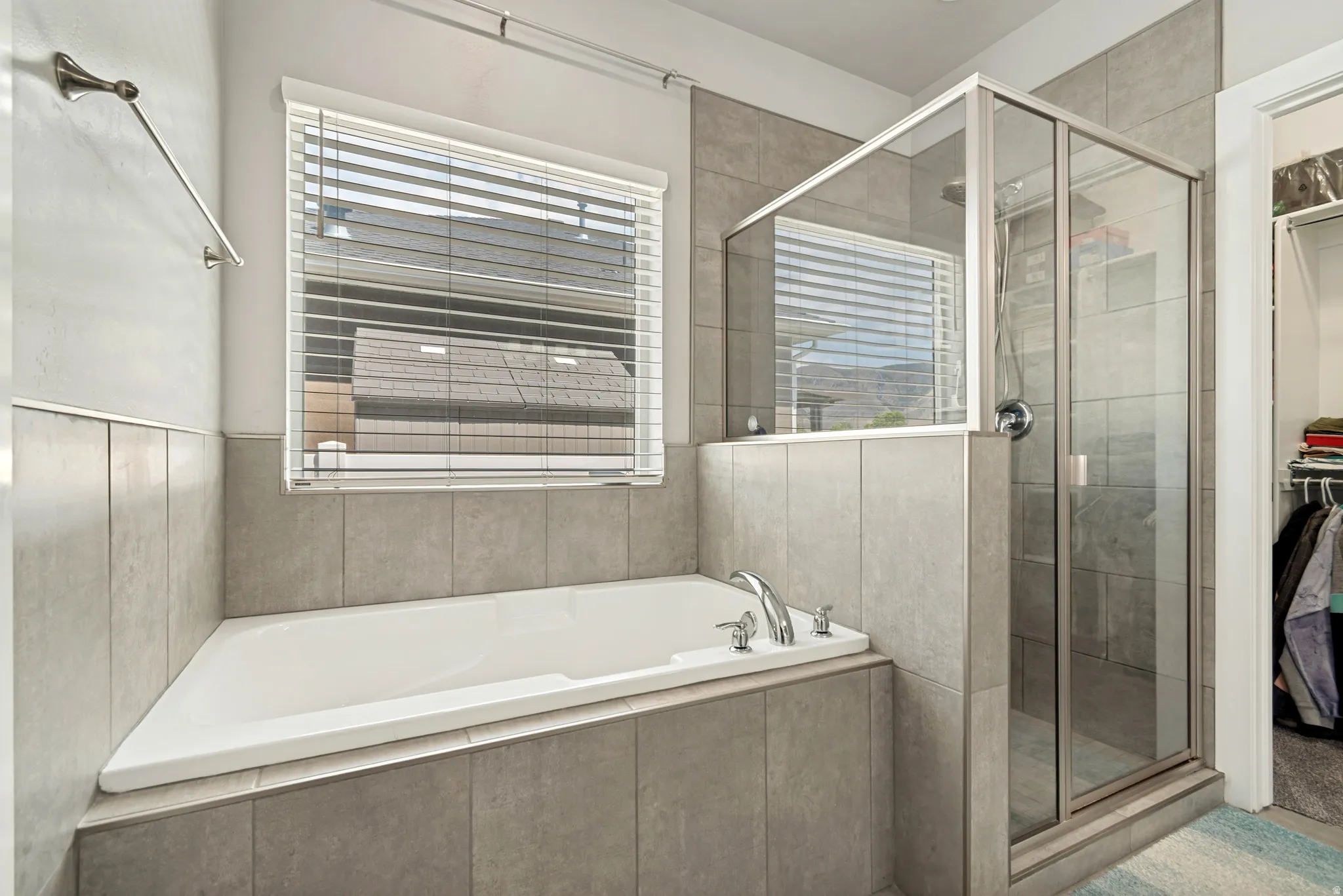 Bathroom featuring a built-in tub, tiled surround, and glass-enclosed shower with chrome fixtures