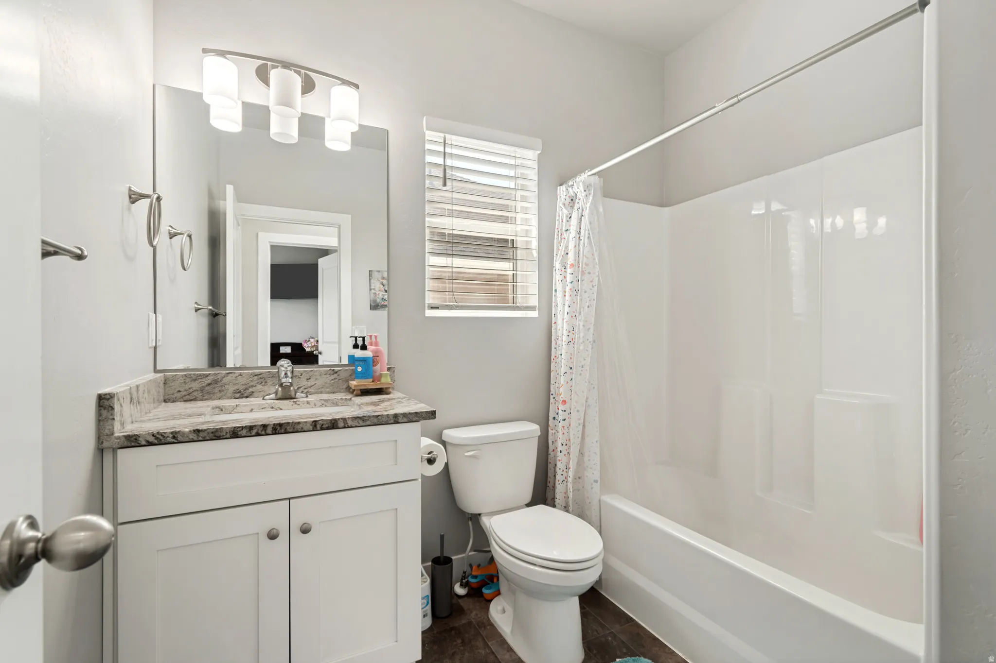 Bathroom featuring a white vanity with slab cabinet doors, a speckled countertop, and a rectangular mirror