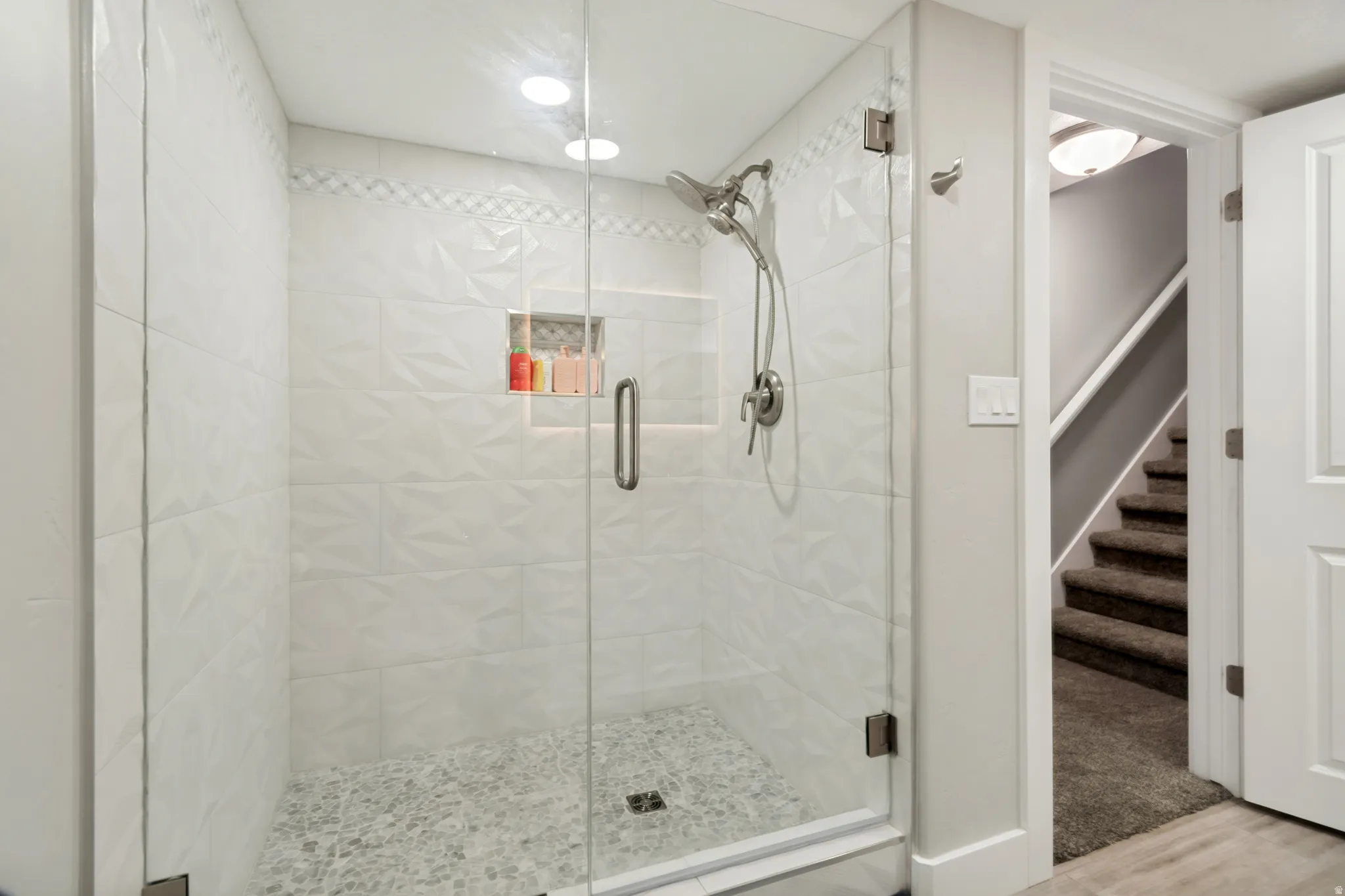 Walk-in shower featuring textured white wall tiles and a pebble floor