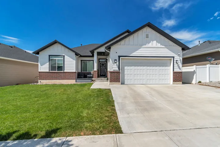 Modern ranch-style home featuring white horizontal siding, dark trim accents, a two-car garage, and a concrete driveway
