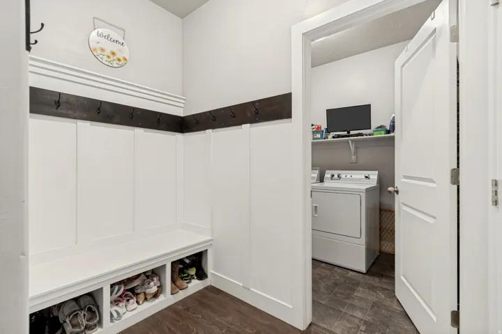 Entryway featuring white wainscoting, a built-in bench with cubby storage, and a dark wood-finish coat rack with hooks