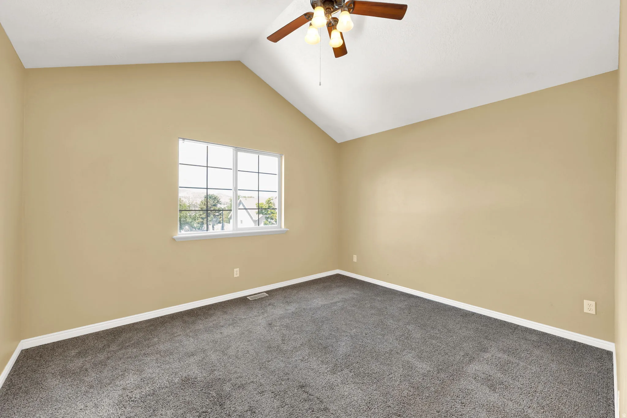 Bedroom featuring vaulted ceilings, a multi-pane window, and neutral-toned walls