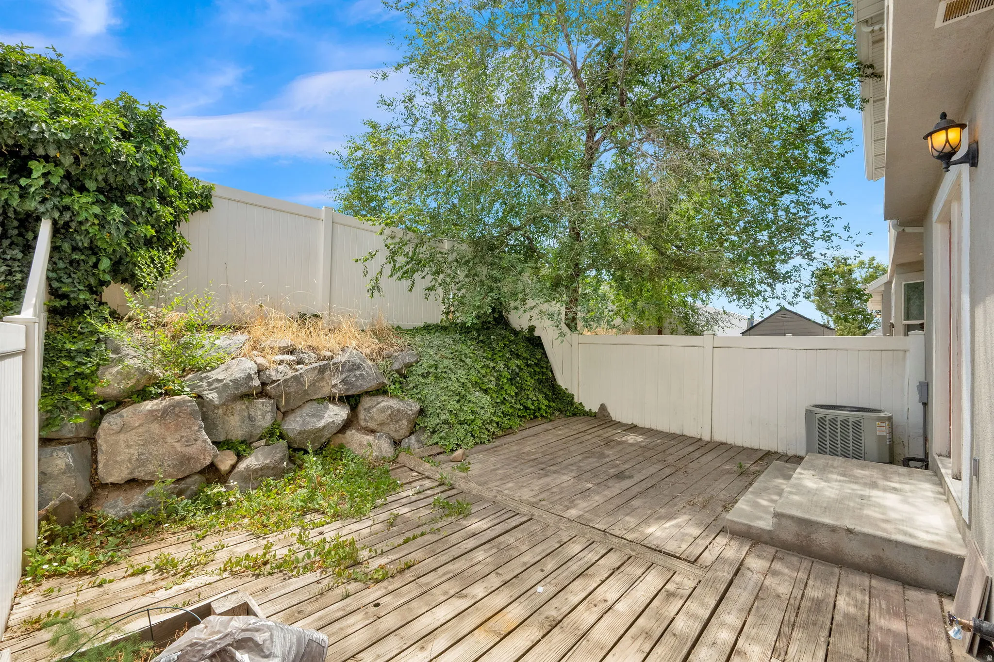 Wood-finish deck with a rock retaining wall and surrounding greenery