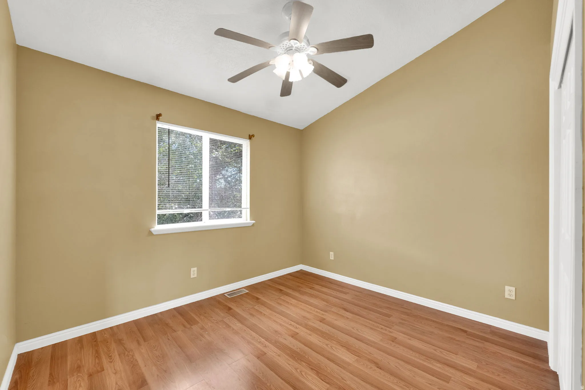 Room featuring wood-finish flooring, a vaulted ceiling, and a ceiling fan with integrated lighting