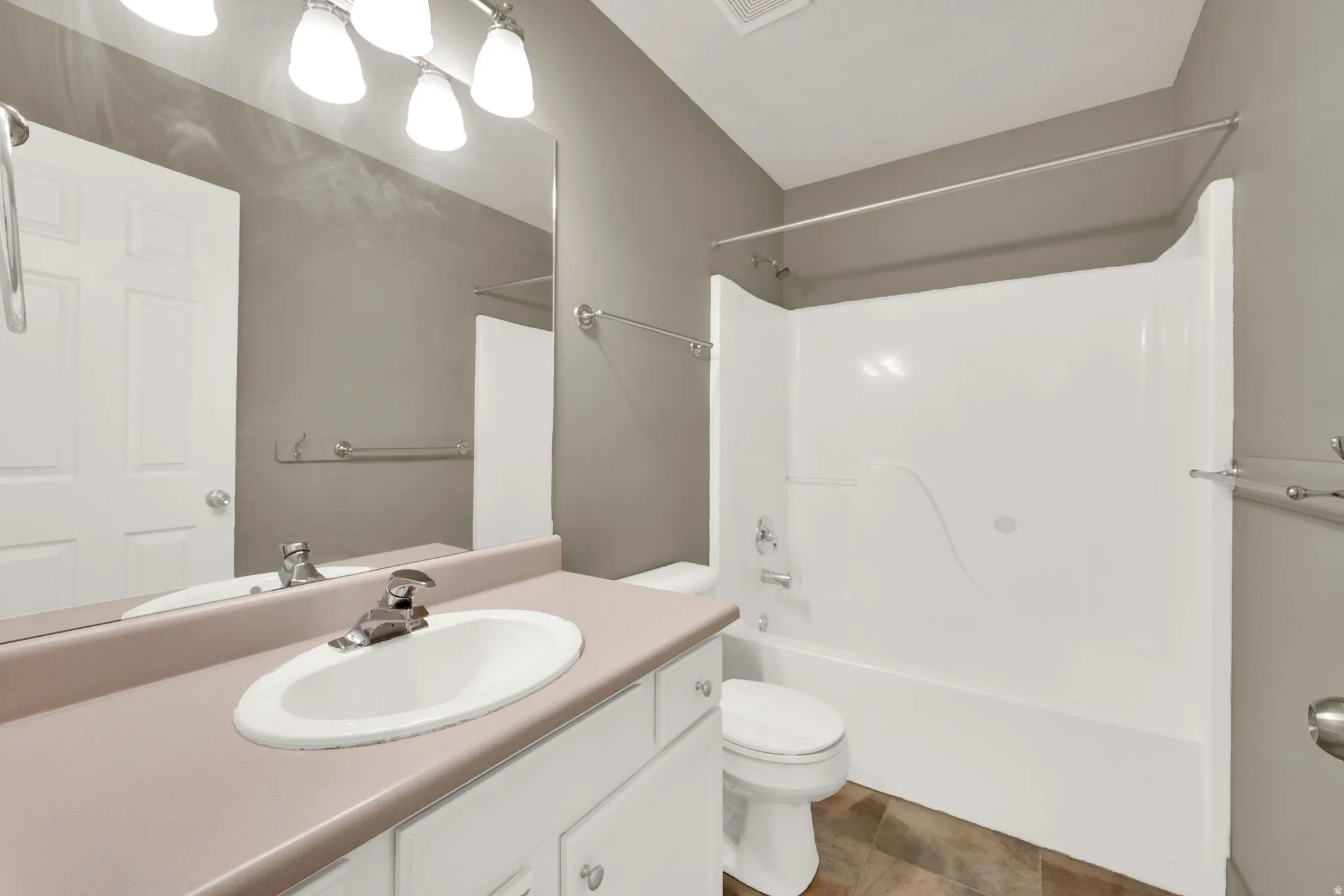 Bathroom featuring a vanity with an integrated sink, a full wall mirror, and a combination shower and tub with a white surround