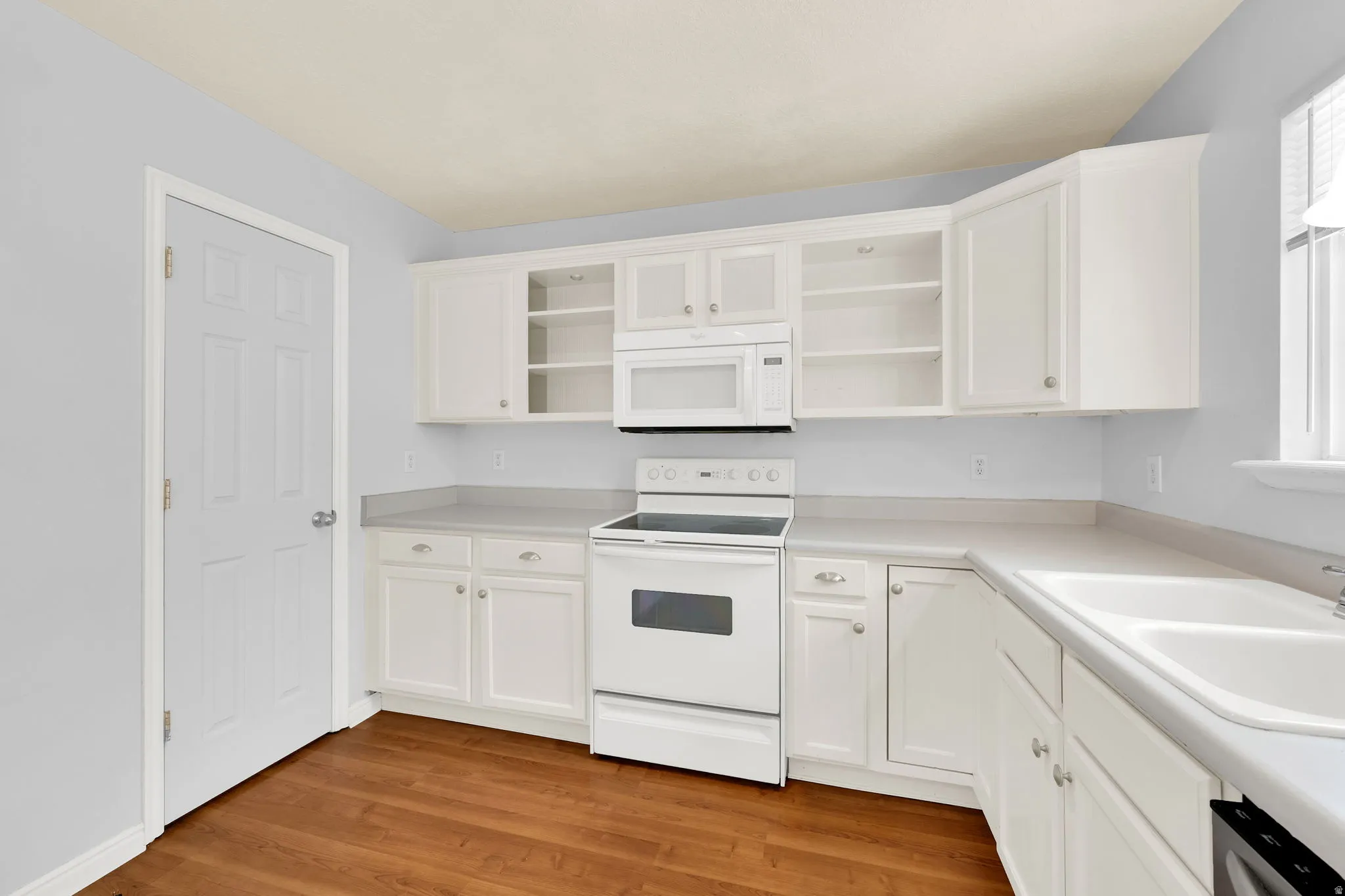 Kitchen featuring white cabinetry, white appliances, light gray countertops, and wood-finish flooring