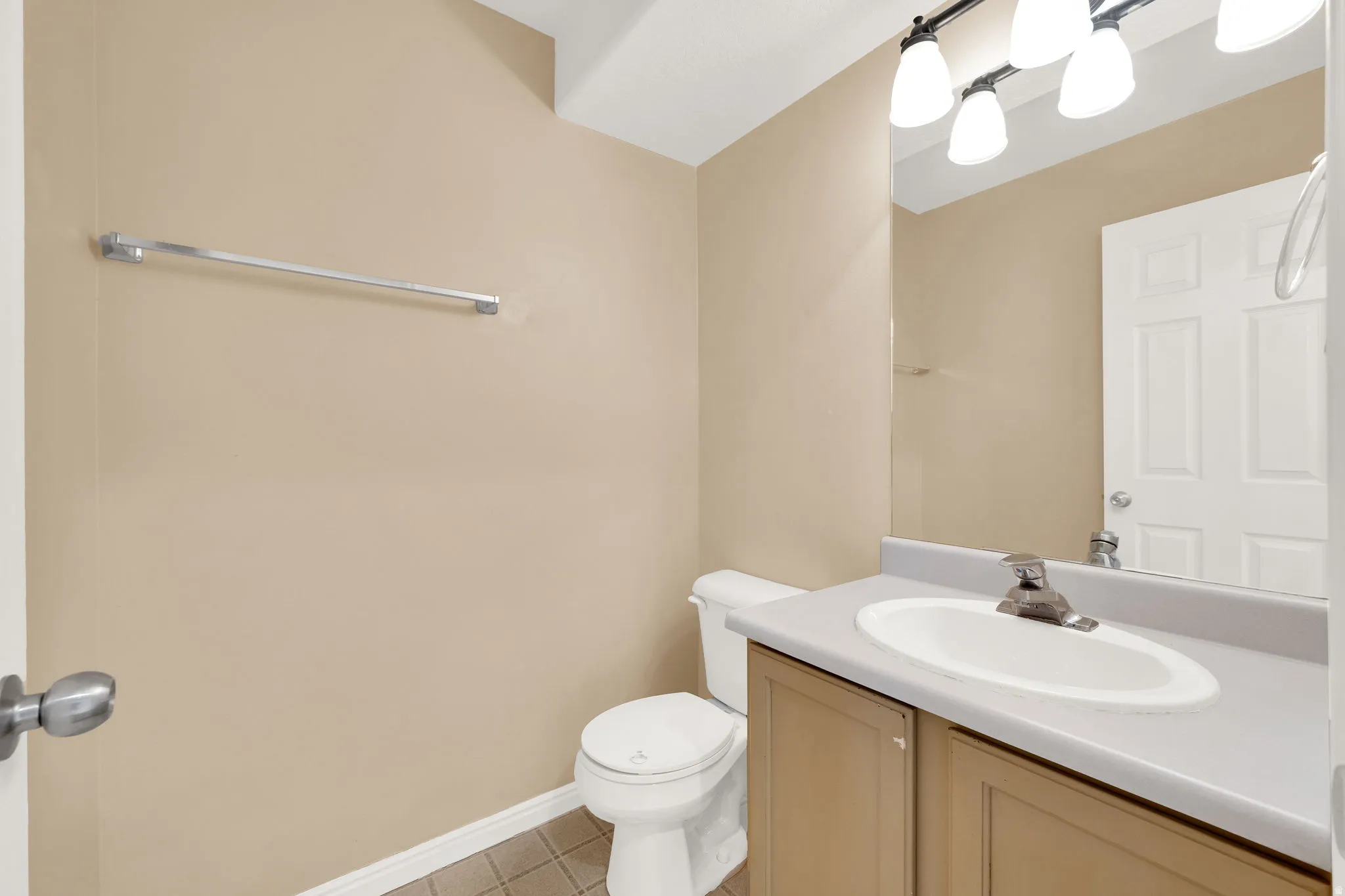 Bathroom featuring a single-sink vanity with a light gray countertop, a three-light fixture, and a large mirror