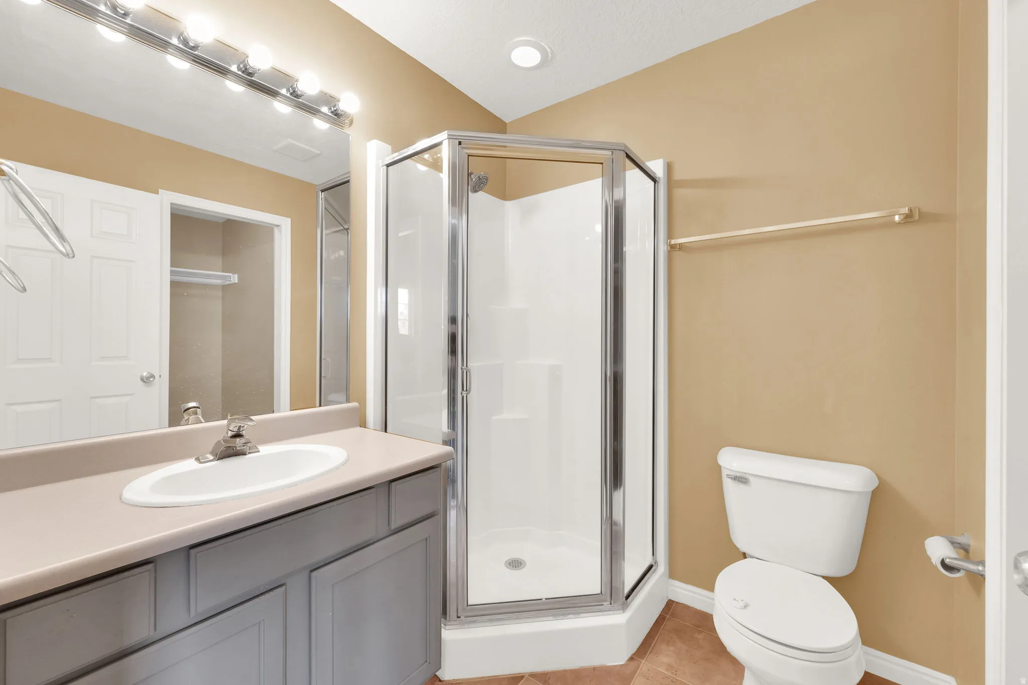 Bathroom featuring an enclosed corner shower, vanity with an integrated sink, and a toilet
