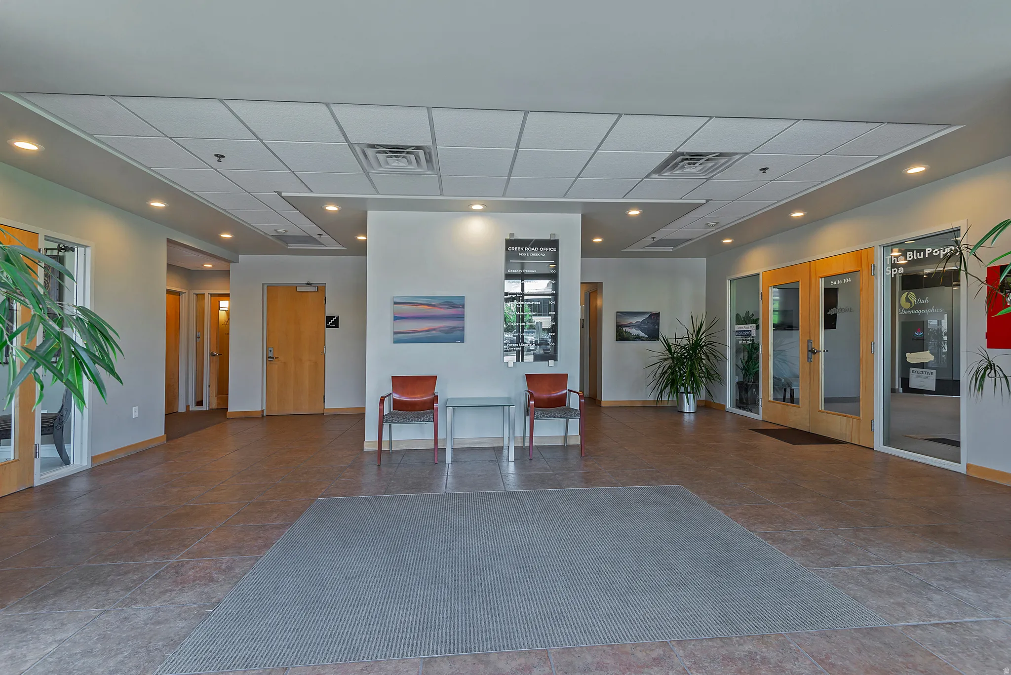 Spacious common area featuring durable tile flooring and a suspended ceiling with recessed lighting