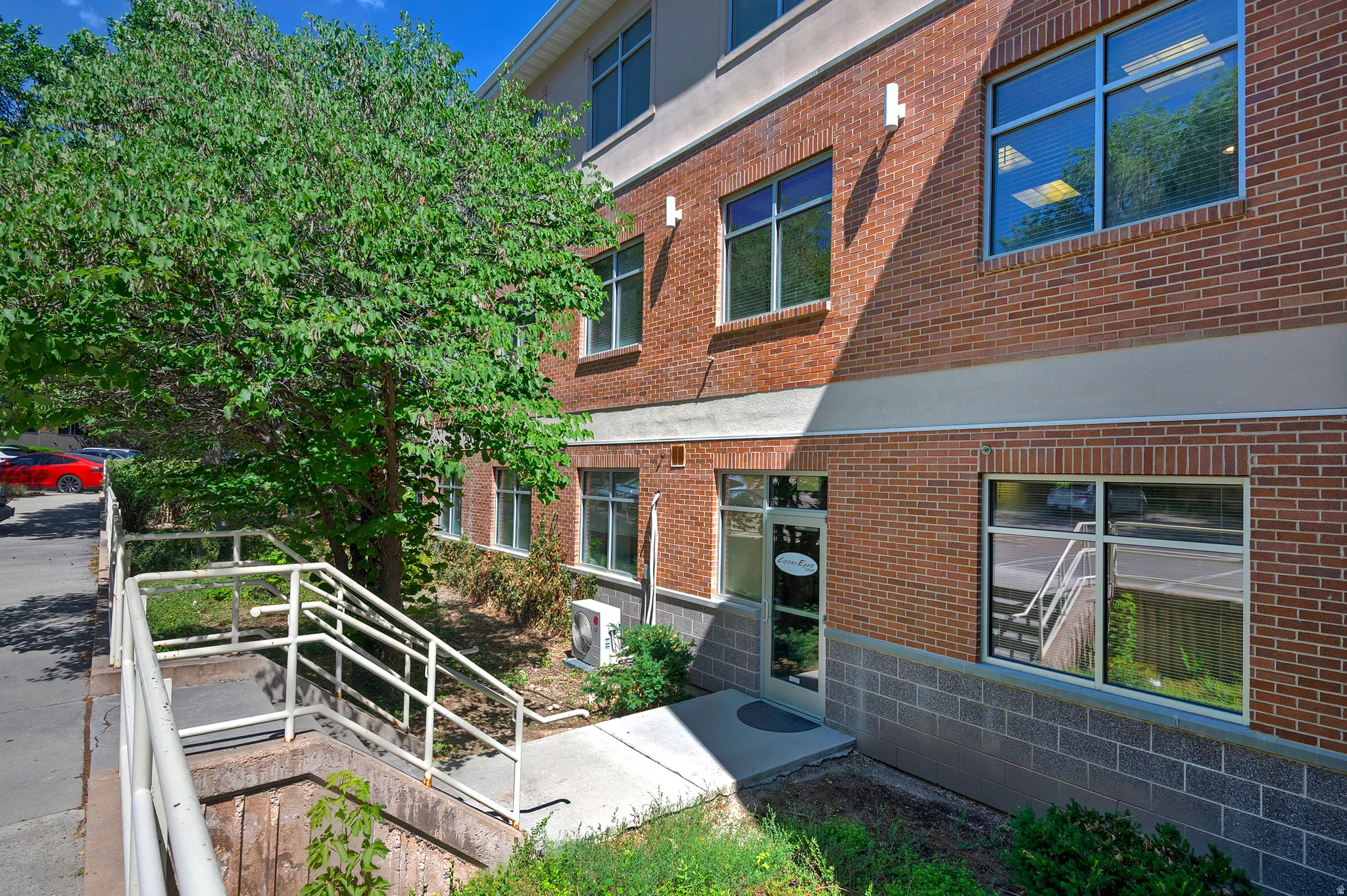 Brick facade building featuring multiple large windows and a prominent entry door