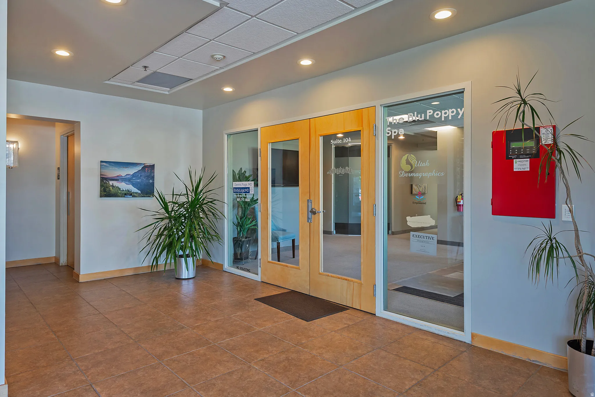 Spacious hallway featuring neutral wall finishes, recessed lighting, and durable tile flooring