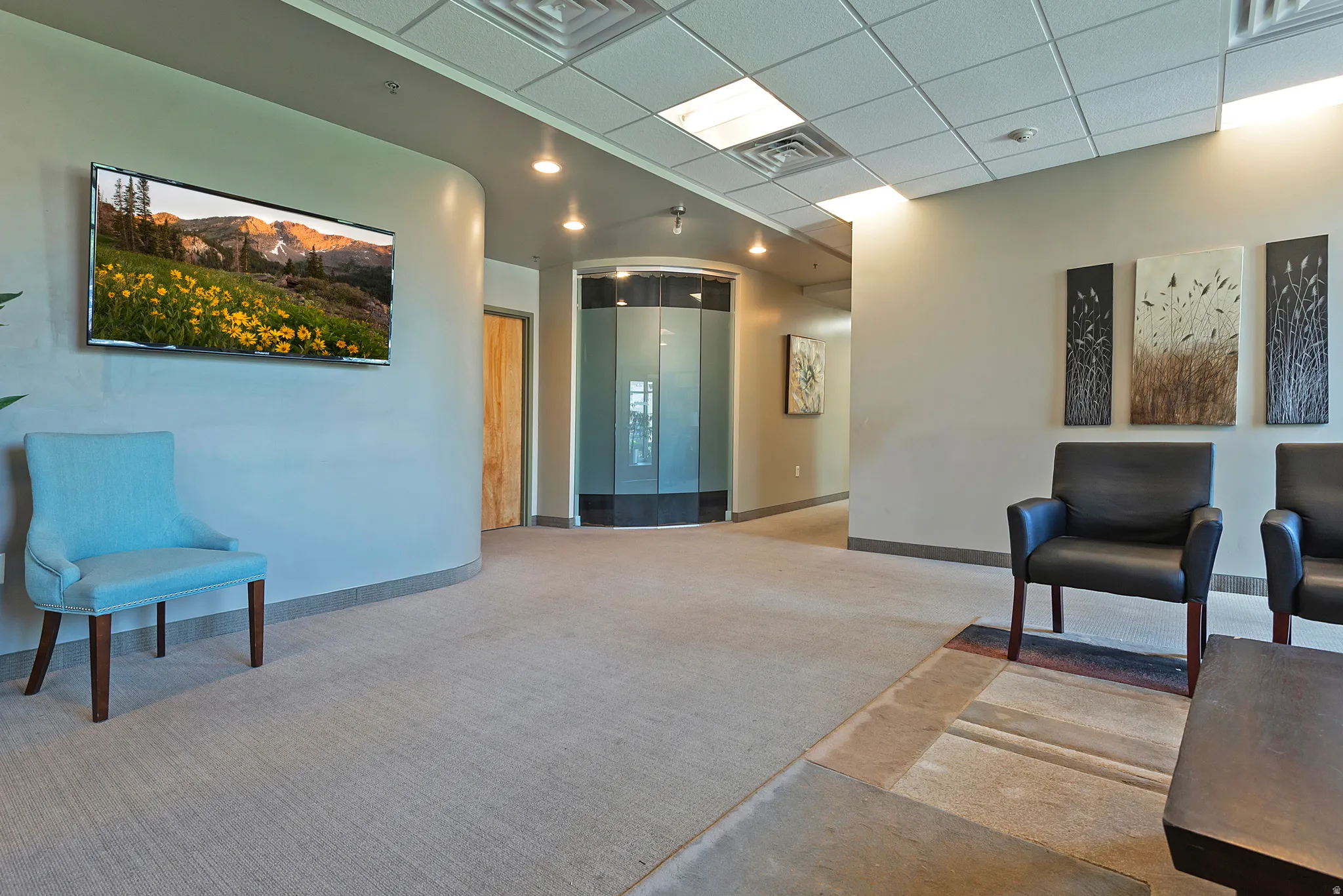 Spacious interior with neutral carpeting and a dropped ceiling with recessed lighting