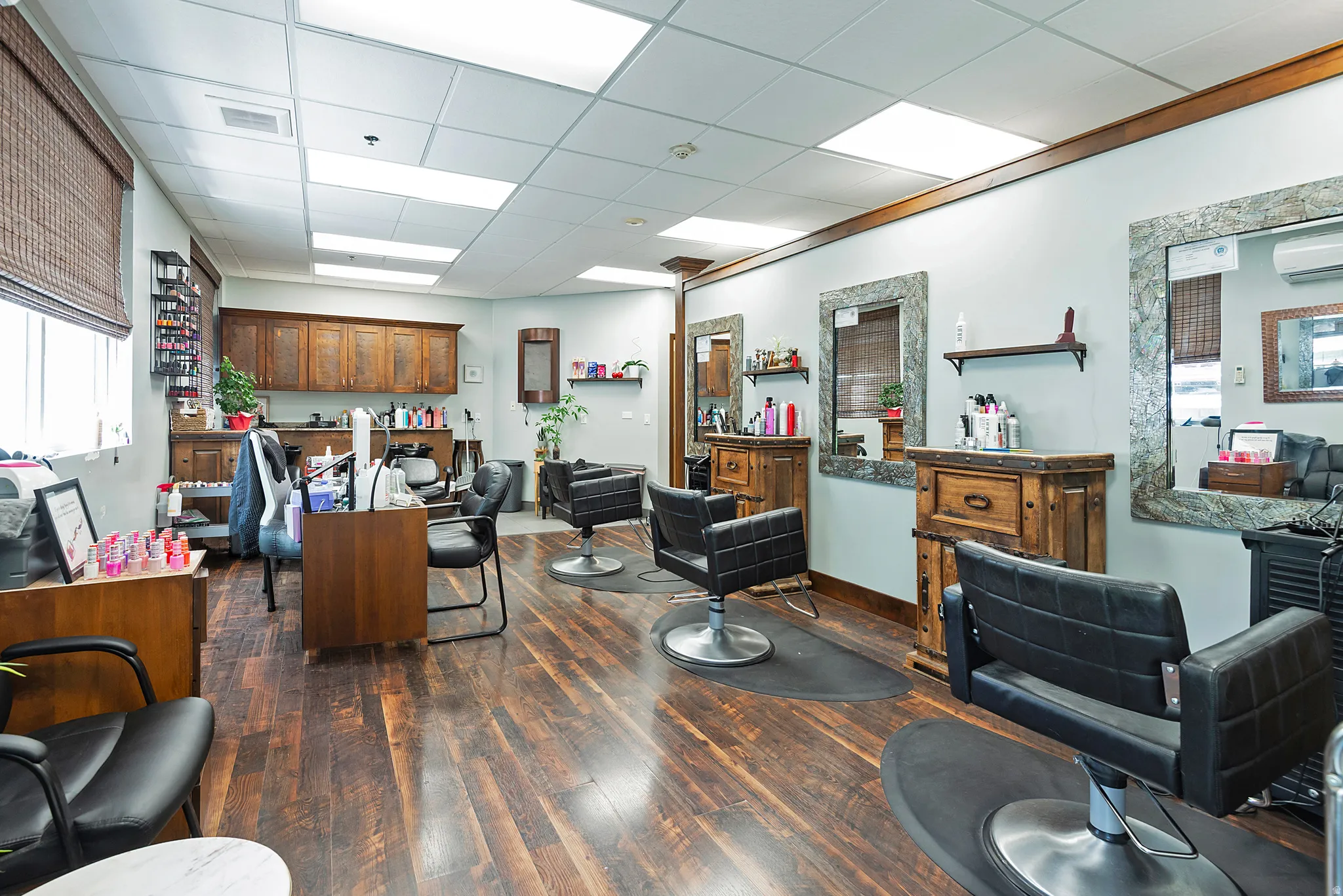 Spacious commercial interior featuring wood-finish flooring, recessed lighting, and multiple workstation areas